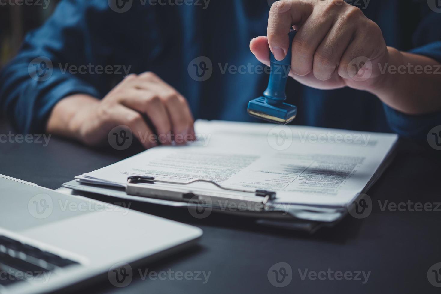 Man stamping approval of work finance banking or investment marketing documents on desk. photo