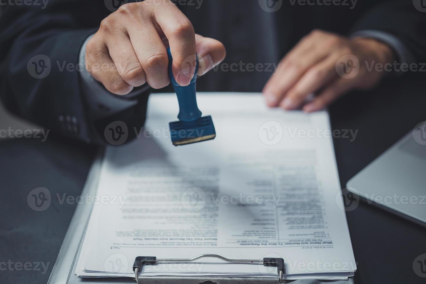 Man stamping approval of work finance banking or investment marketing documents on desk. photo