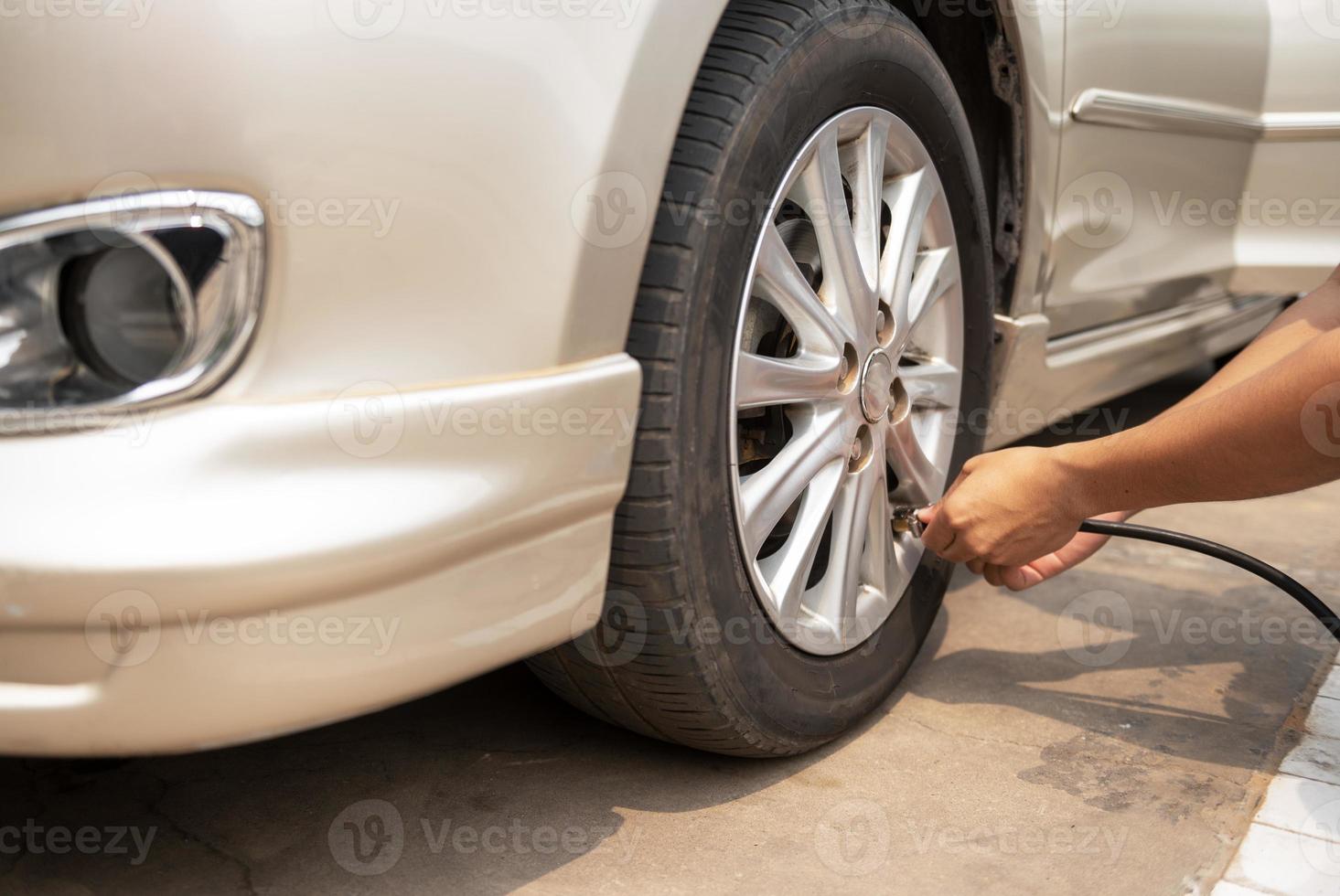 Asian man inflating tires at gas station And he's looking at the dial of the auto-inflator to check the pressure level, inflate the tires. photo