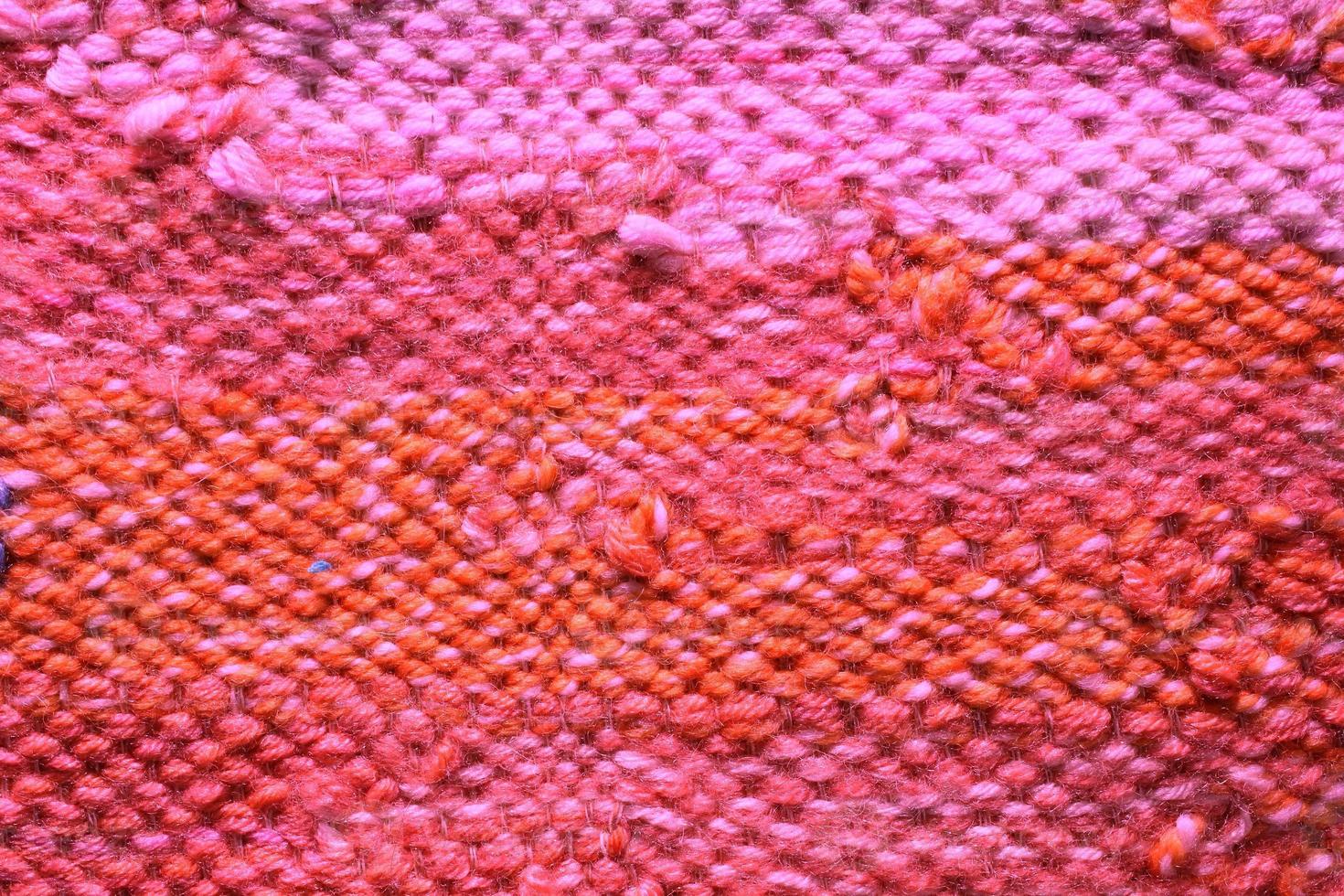 Woven pink and orange wool fabric texture. Hand knitted textile canvas background. Patchwork carpet backdrop. Factory material threads. Abstract design. Close-up, mockup, top view photo