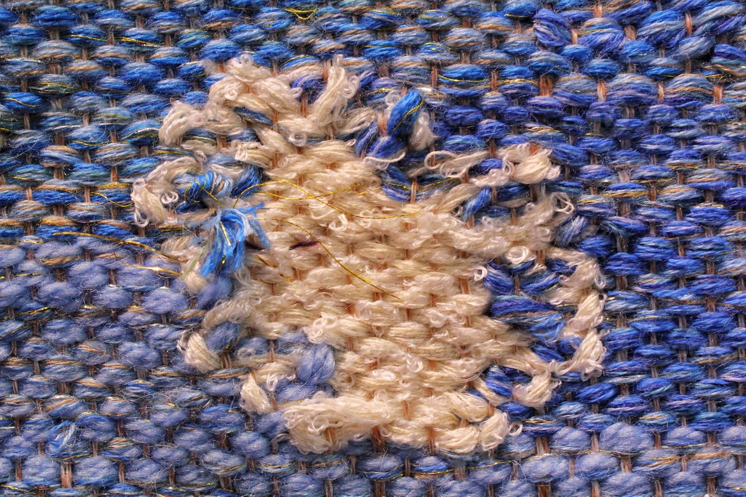 Woven blue and beige wool fabric texture. Hand knitted textile canvas background. Patchwork carpet backdrop. Factory material threads. Abstract design. Close-up, mockup, top view photo