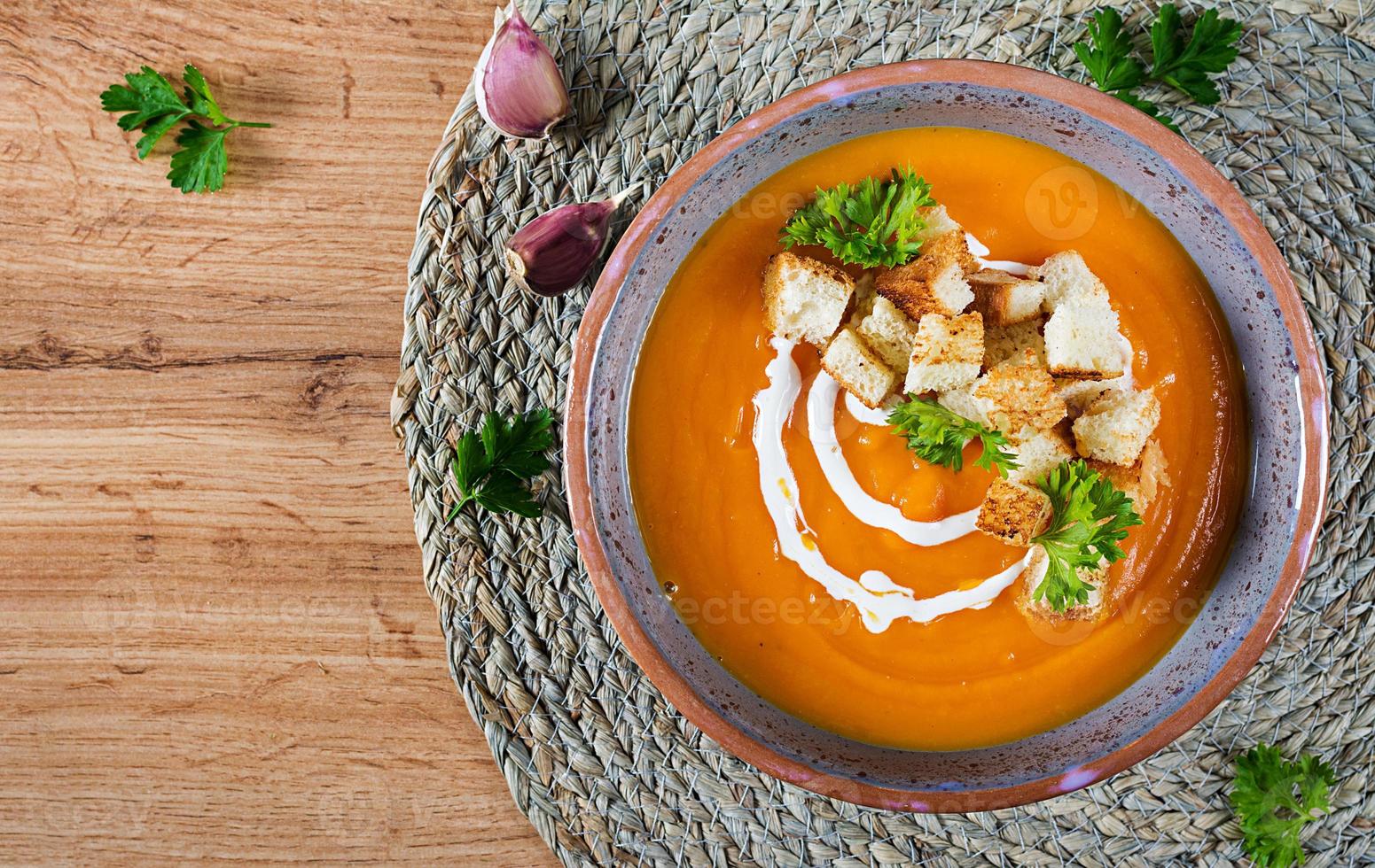 Pumpkin soup in a bowl served with parsley and croutons. Vegan soup. Thanksgiving day food. Halloween meal. Top view photo