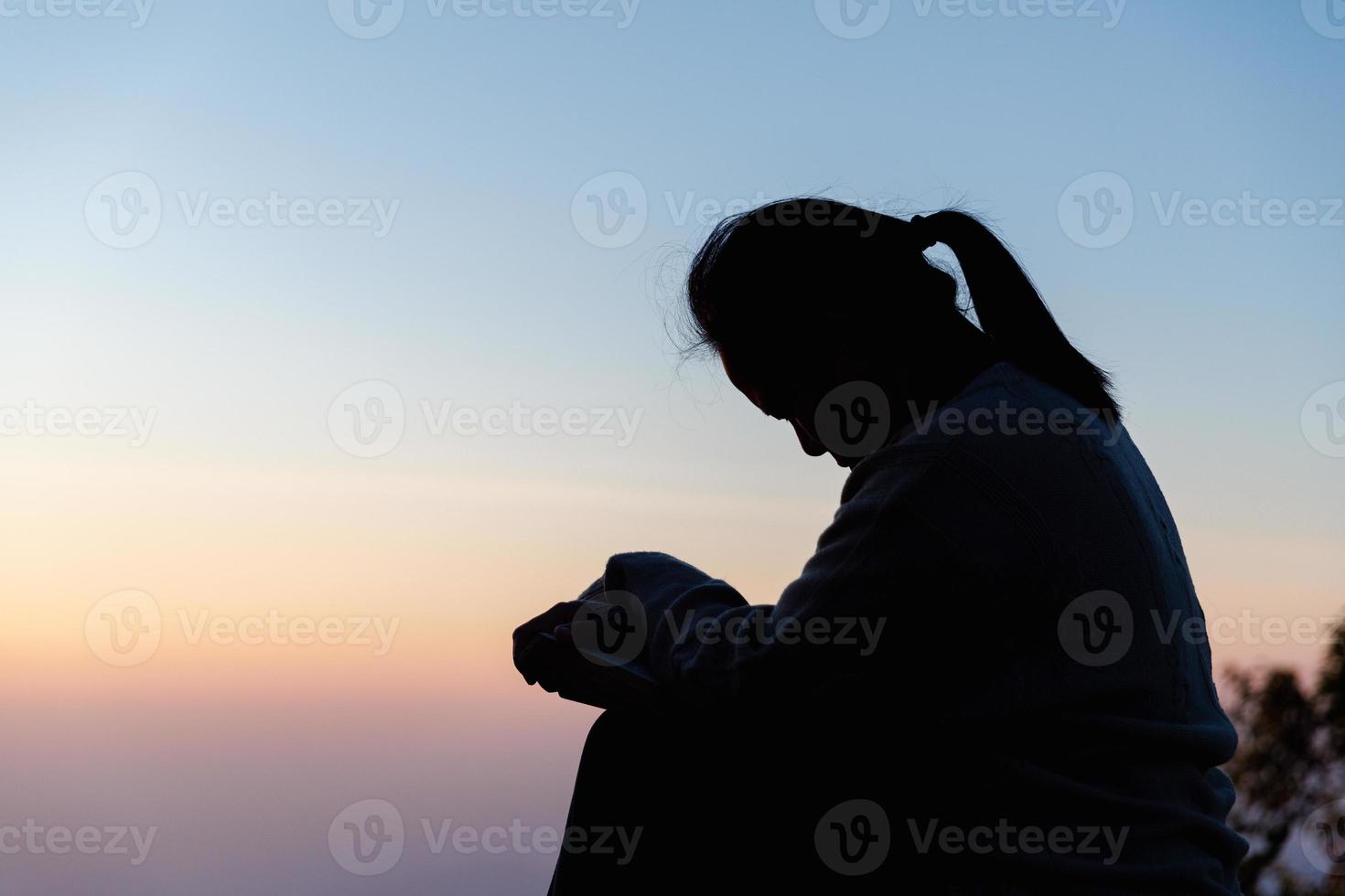 Silhouette of woman kneeling down praying for worship God at sky background. Christians pray to jesus christ for calmness. In morning people got to a quiet place and prayed. copy space. photo