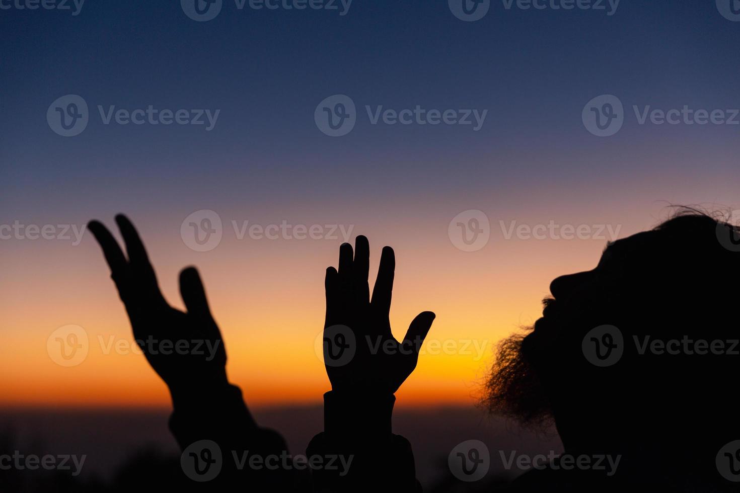 Silhouette of man kneeling down praying for worship God at sky background. Christians pray to jesus christ for calmness. In morning people got to a quiet place and prayed. copy space. photo