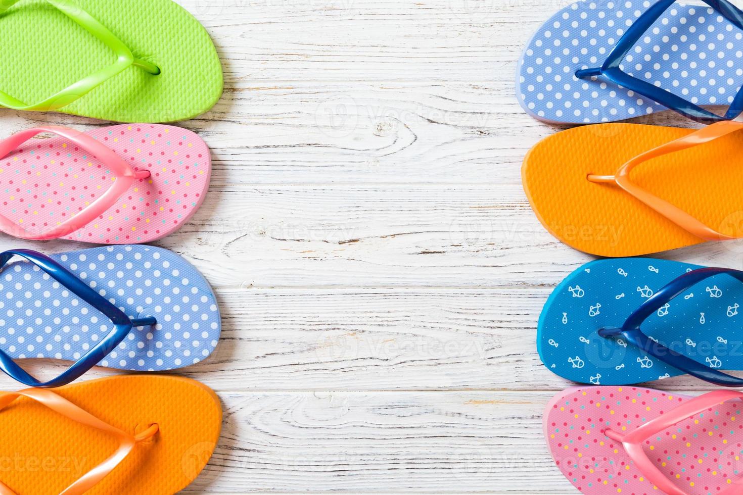 a lot of flip flop colored sandals, summer vacation on wooden background, copy space top view photo