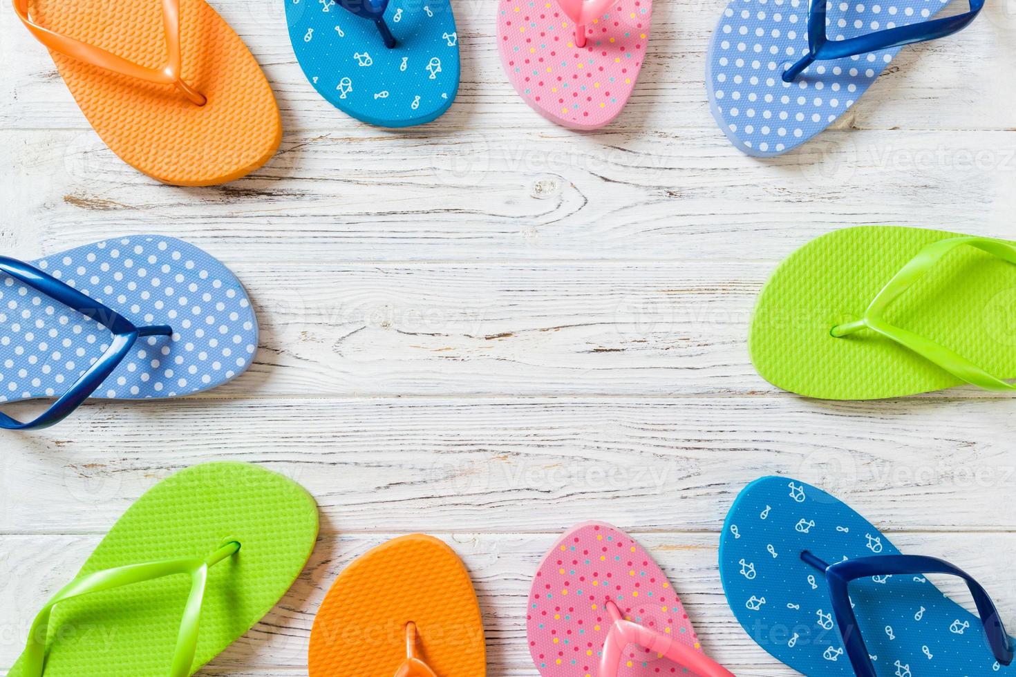 a lot of flip flop colored sandals, summer vacation on wooden background, copy space top view photo