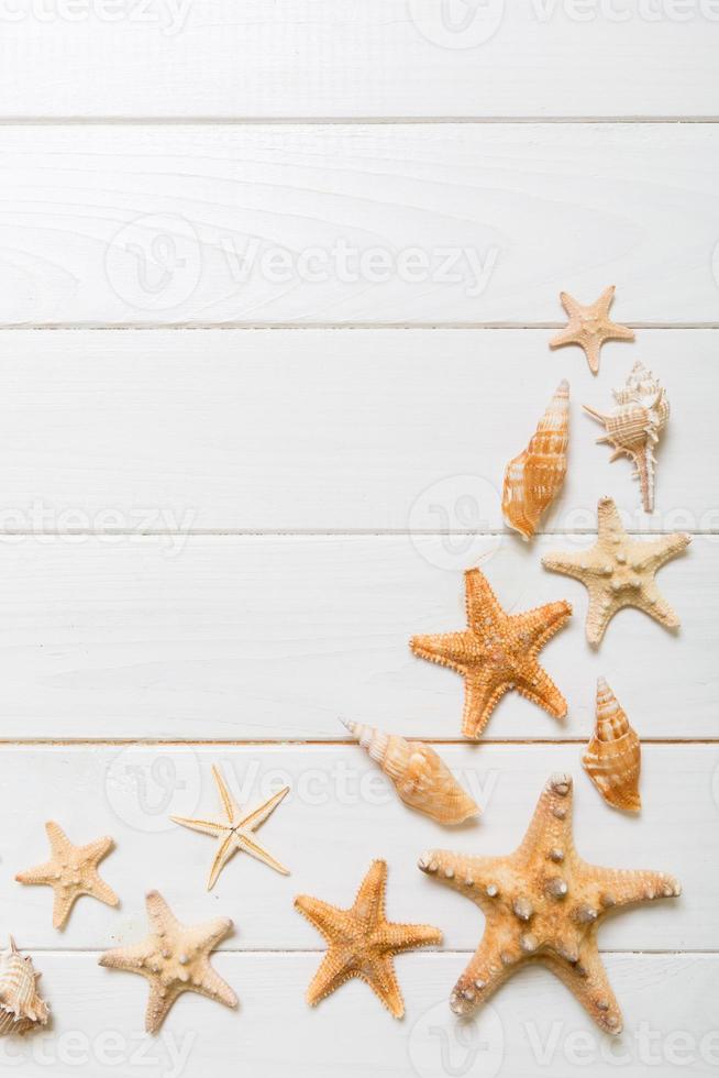 Summertime wooden table with starfish and seashells on a white background top view. Copy space background, summer concept photo