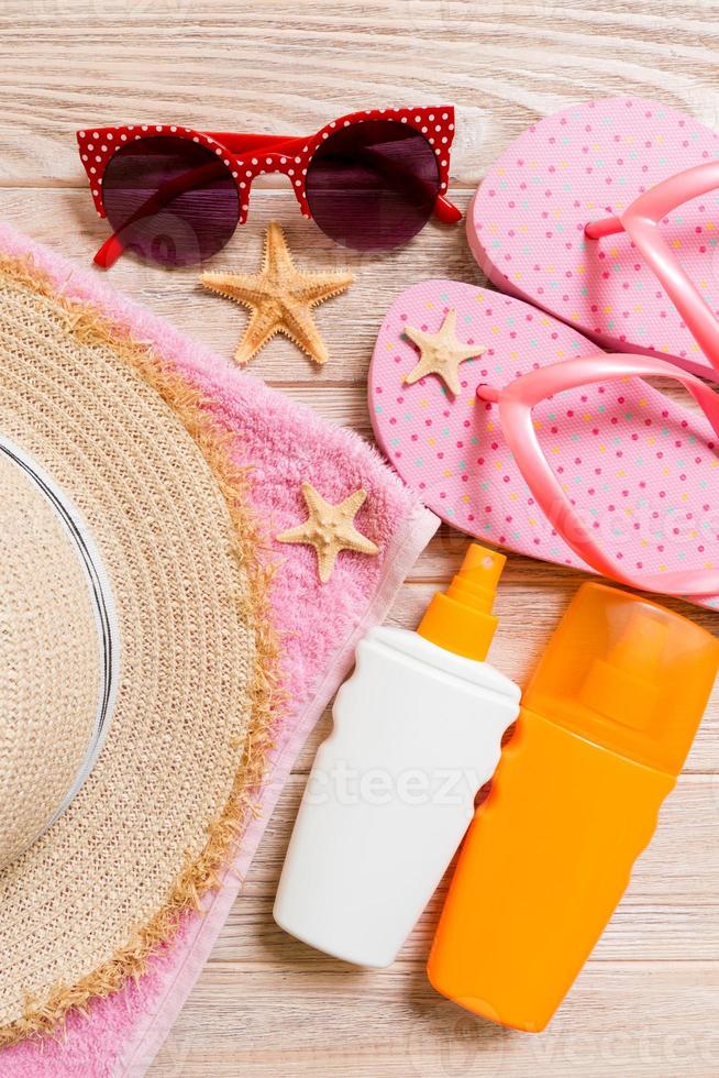 chanclas, sombrero de paja, estrellas de mar, botella de protector solar, spray de loción corporal en la vista superior de fondo de madera. Fondo de accesorios de mar de playa de verano laicos plana, concepto de vaation foto