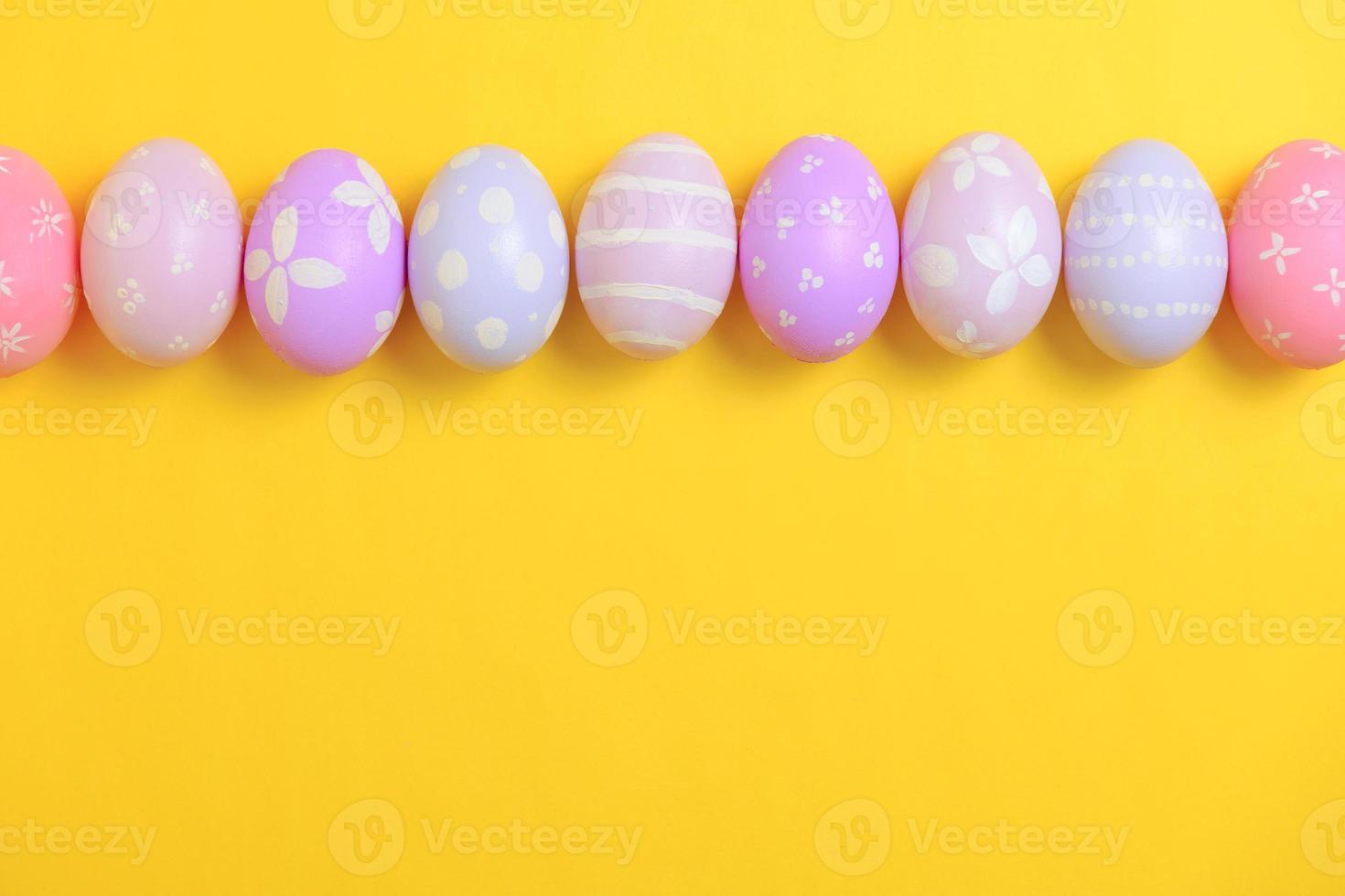 Happy easter holiday celebration concept. Group of painted colourful eggs decoration on a yellow background. Seasonal religion tradition design. Top view, flat lay, copy space. photo