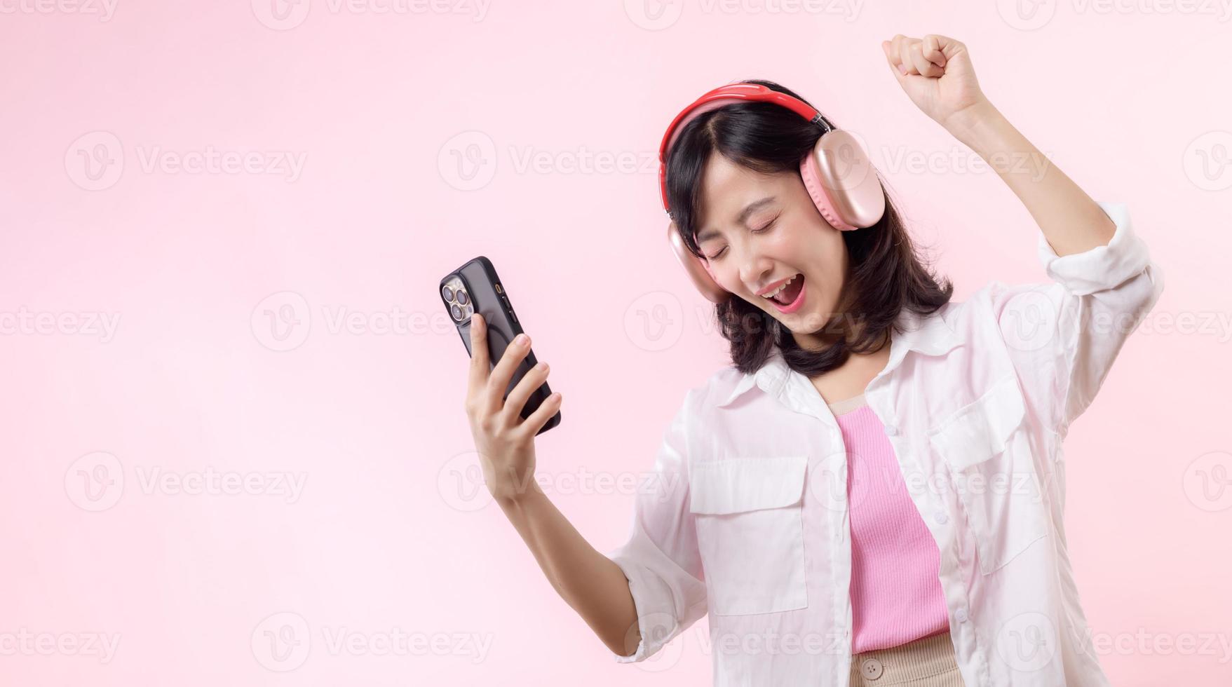 People emotions, lifestyle leisure and beauty concept. Carefree good-looking asian woman close eyes and dancing relaxed with smartphone, listening music in wireless headphones photo
