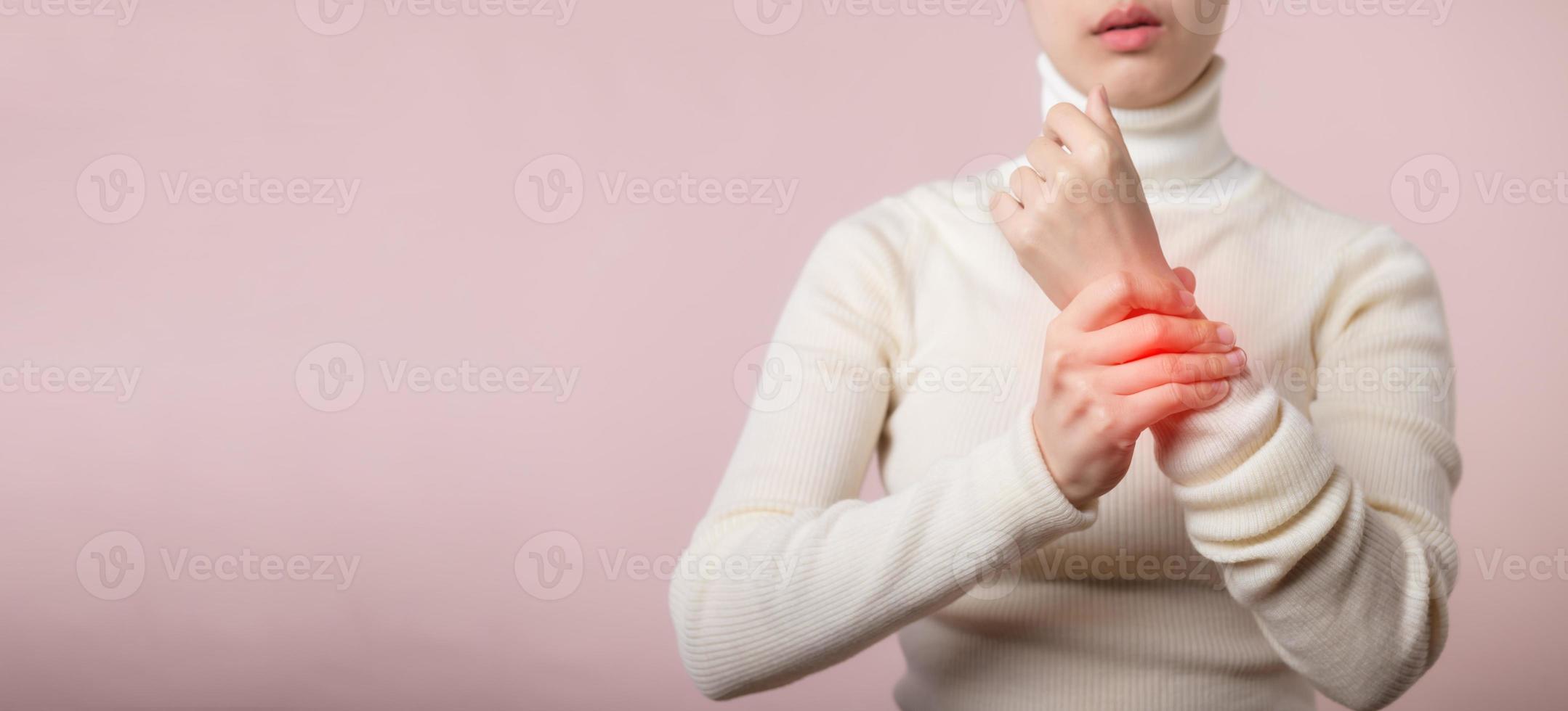 Young asian woman with white sweater cloth suffering from wrist hand pain injury. Causes of hurt include carpal tunnel syndrome, fractures, arthritis or trigger finger. world health day concept. photo