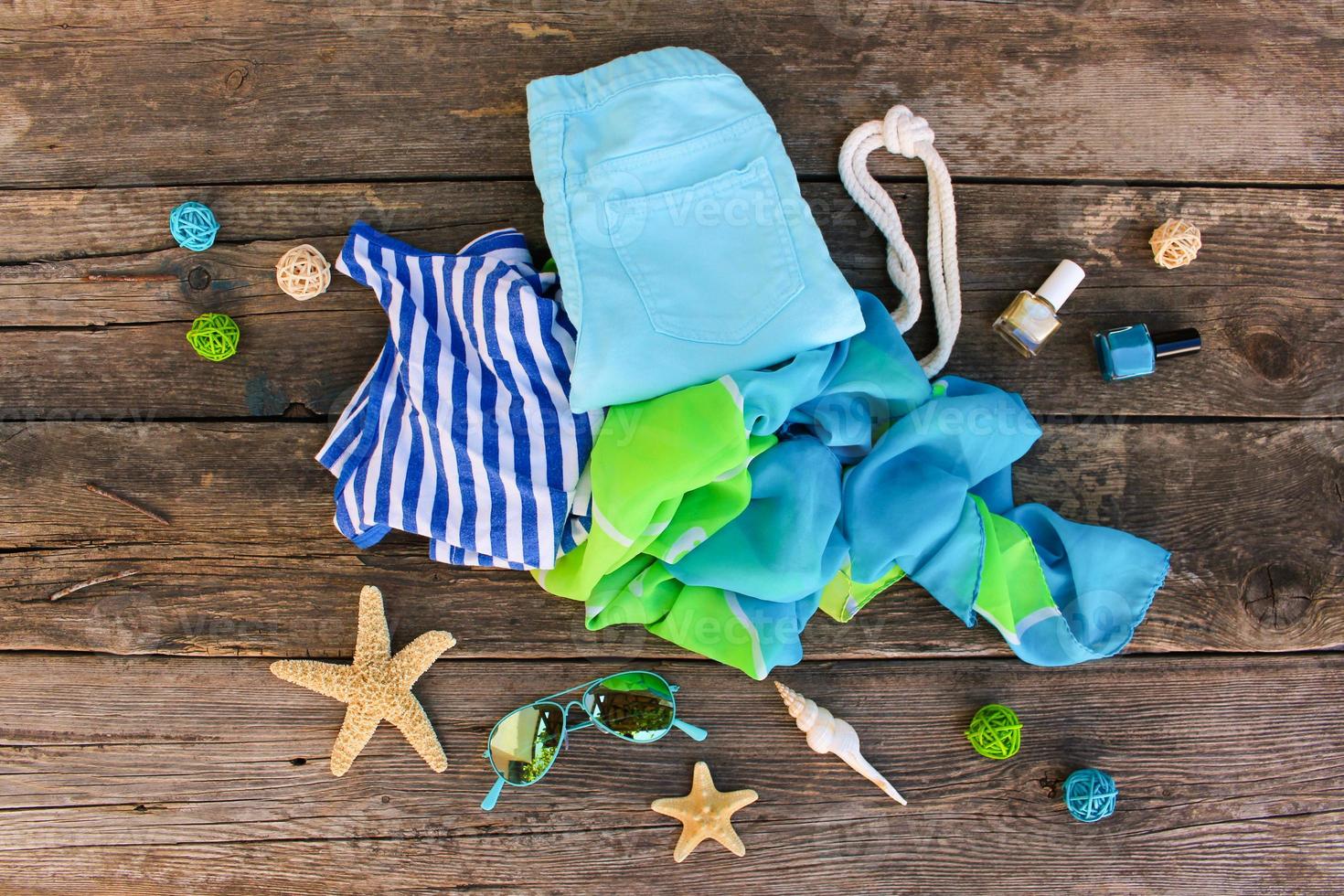 Summer clothes and accessories on old wooden background. Top view, flat lay. photo