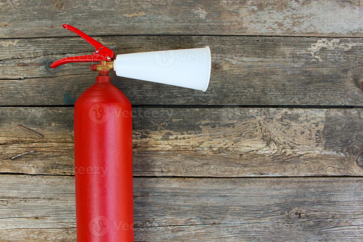 Fire extinguisher on old wooden background. photo