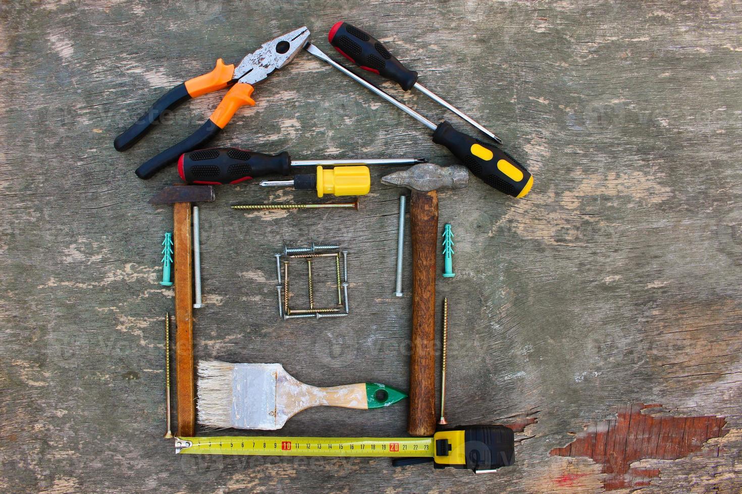 Construction tools in the form of house on wooden background. Top view. Flat lay. photo