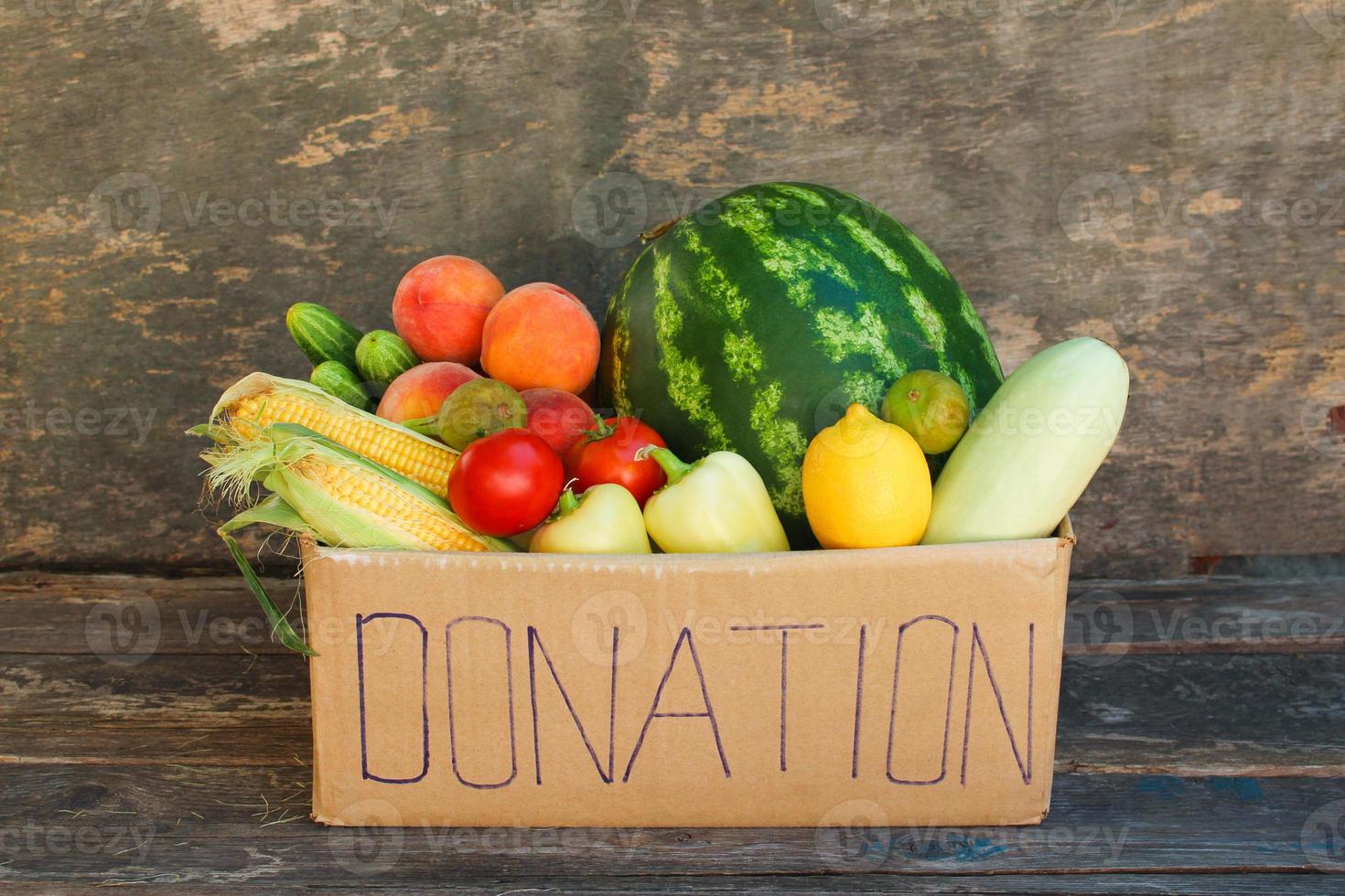 Donation box with vegetables and fruits on the old wooden background. photo