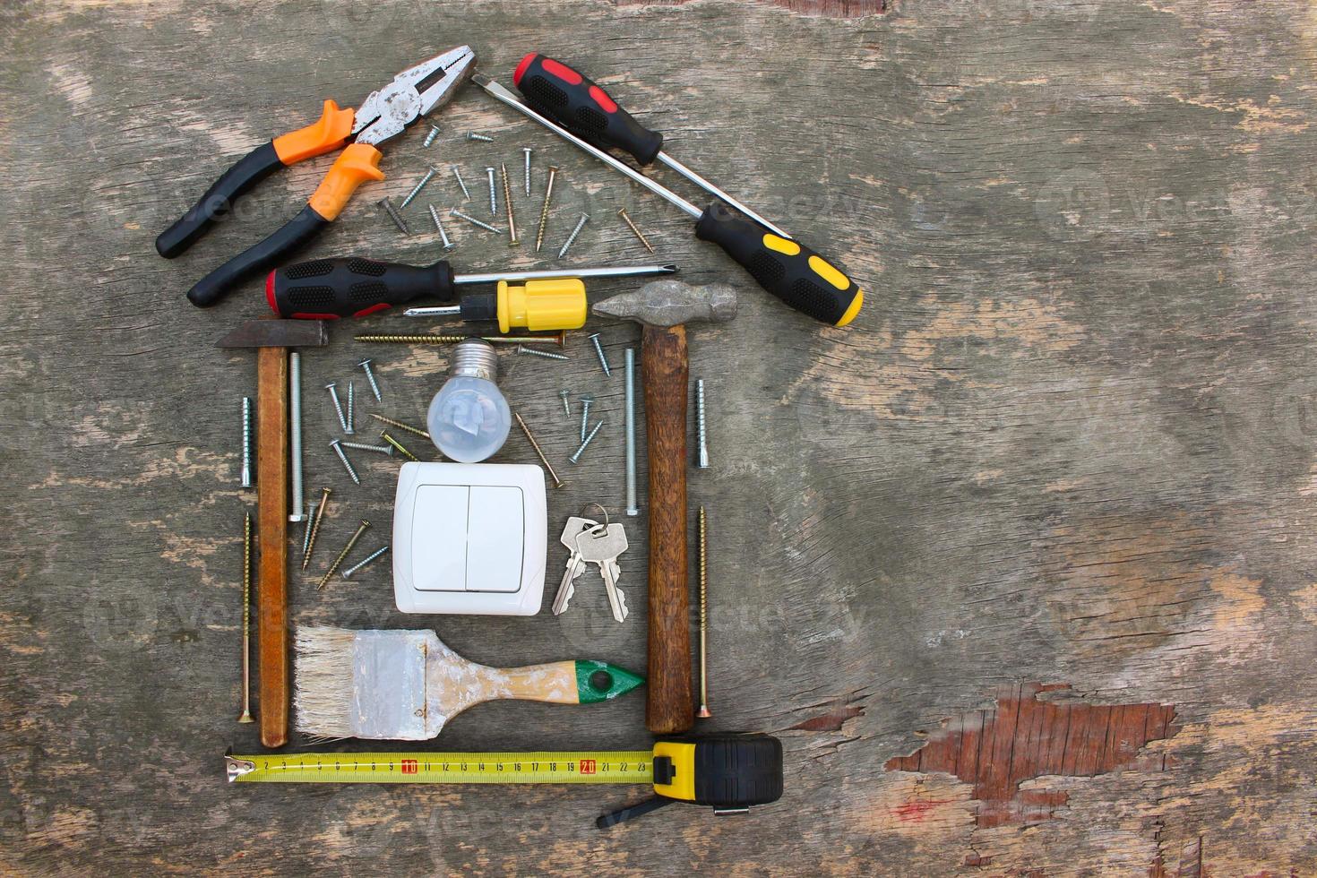 Construction tools in the form of house on wooden background. photo