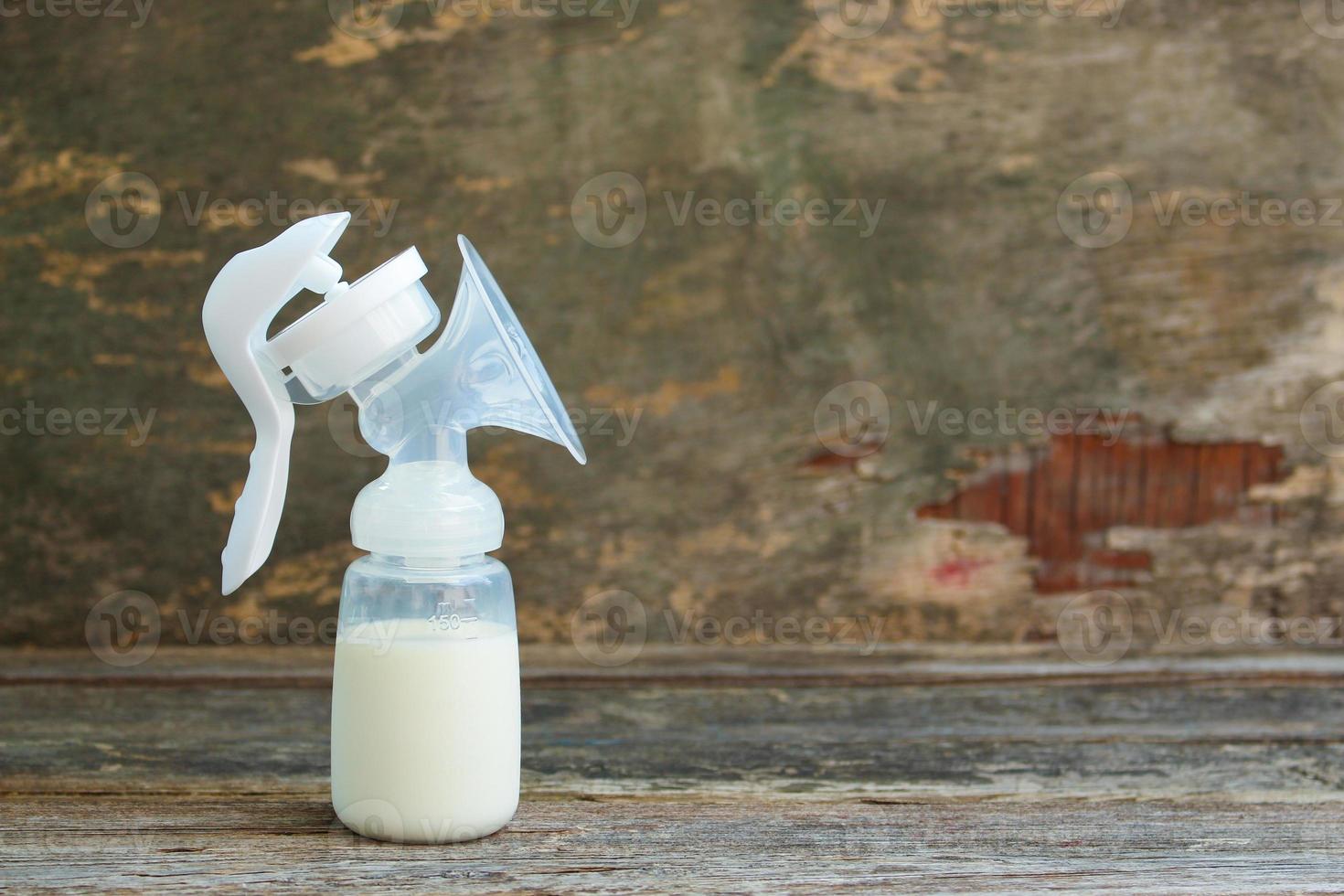 Breast pump of milk on wooden background. photo