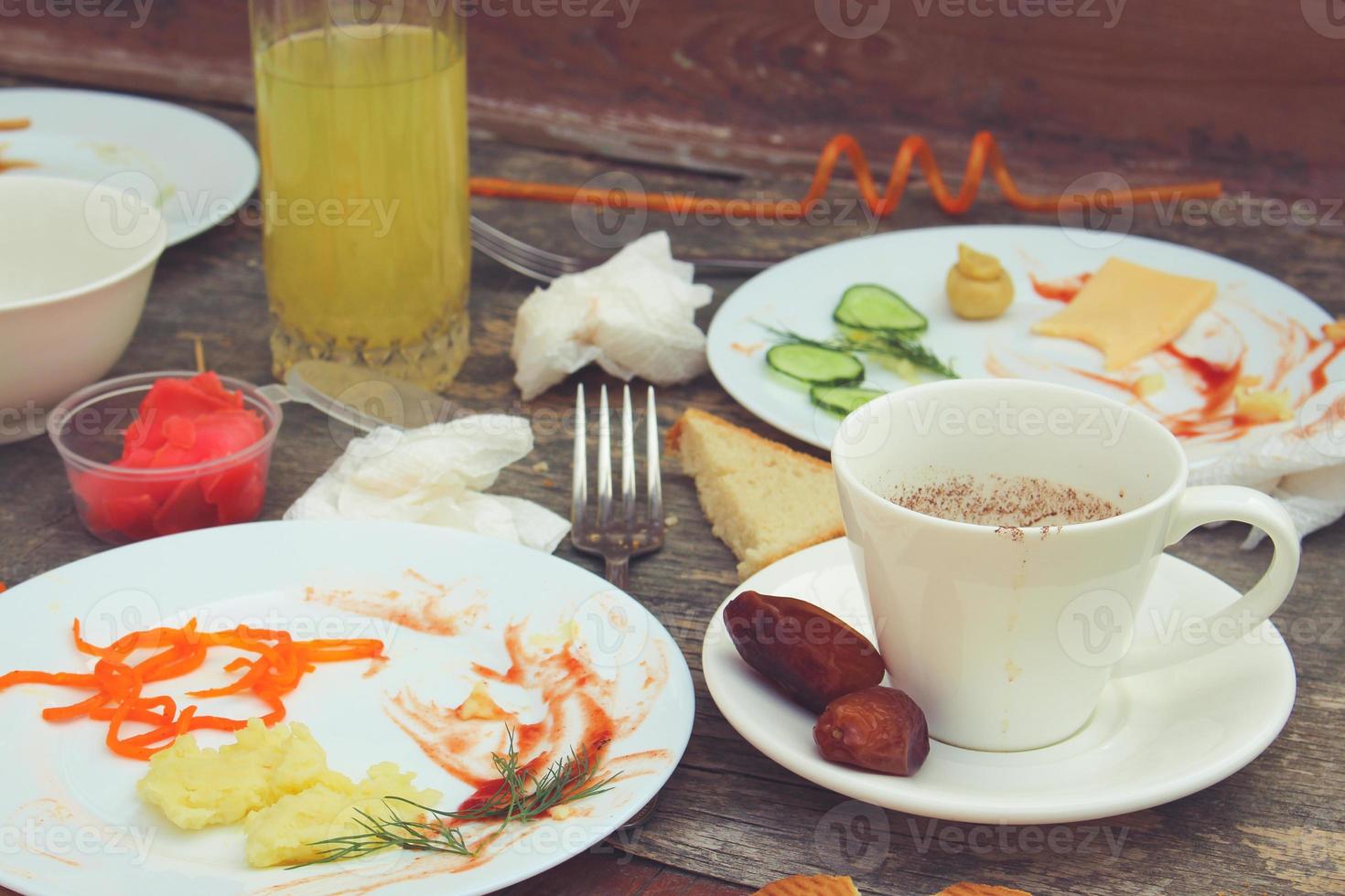 Messy table after party. Leftover food, spilled drinks, dirty dishes. Toned image. photo