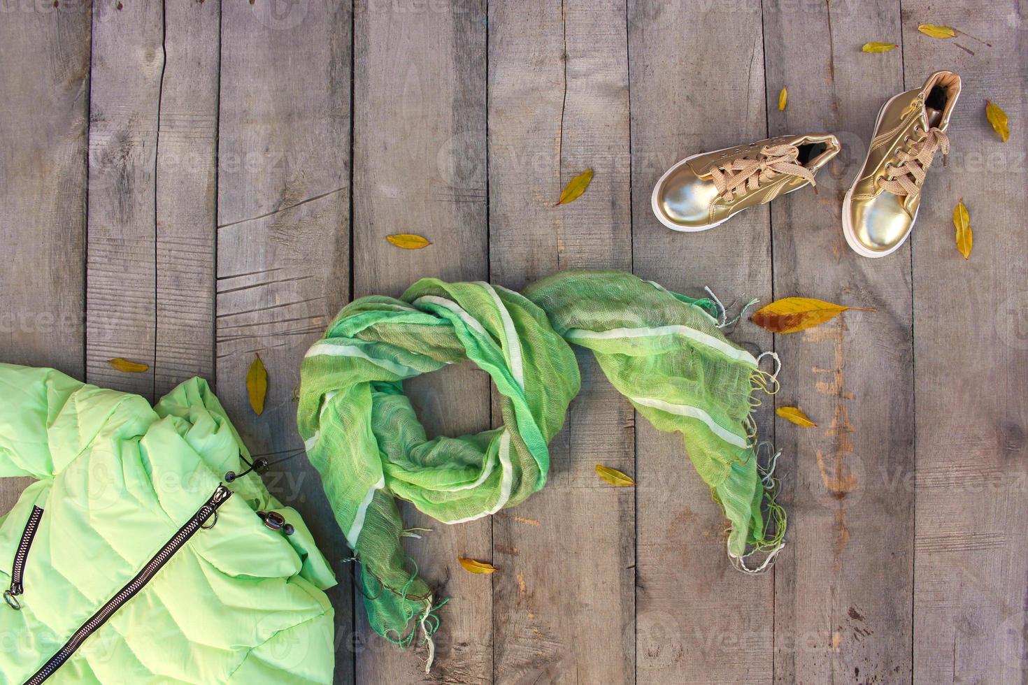 Children's autumn clothes and yellow leaves on old wooden background. Top view. Flat lay. photo