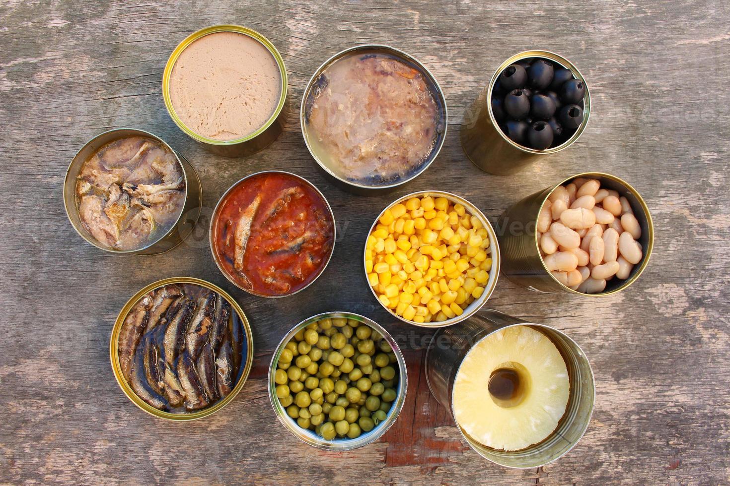 Different open canned food on old wooden background. Top view. Flat lay. photo