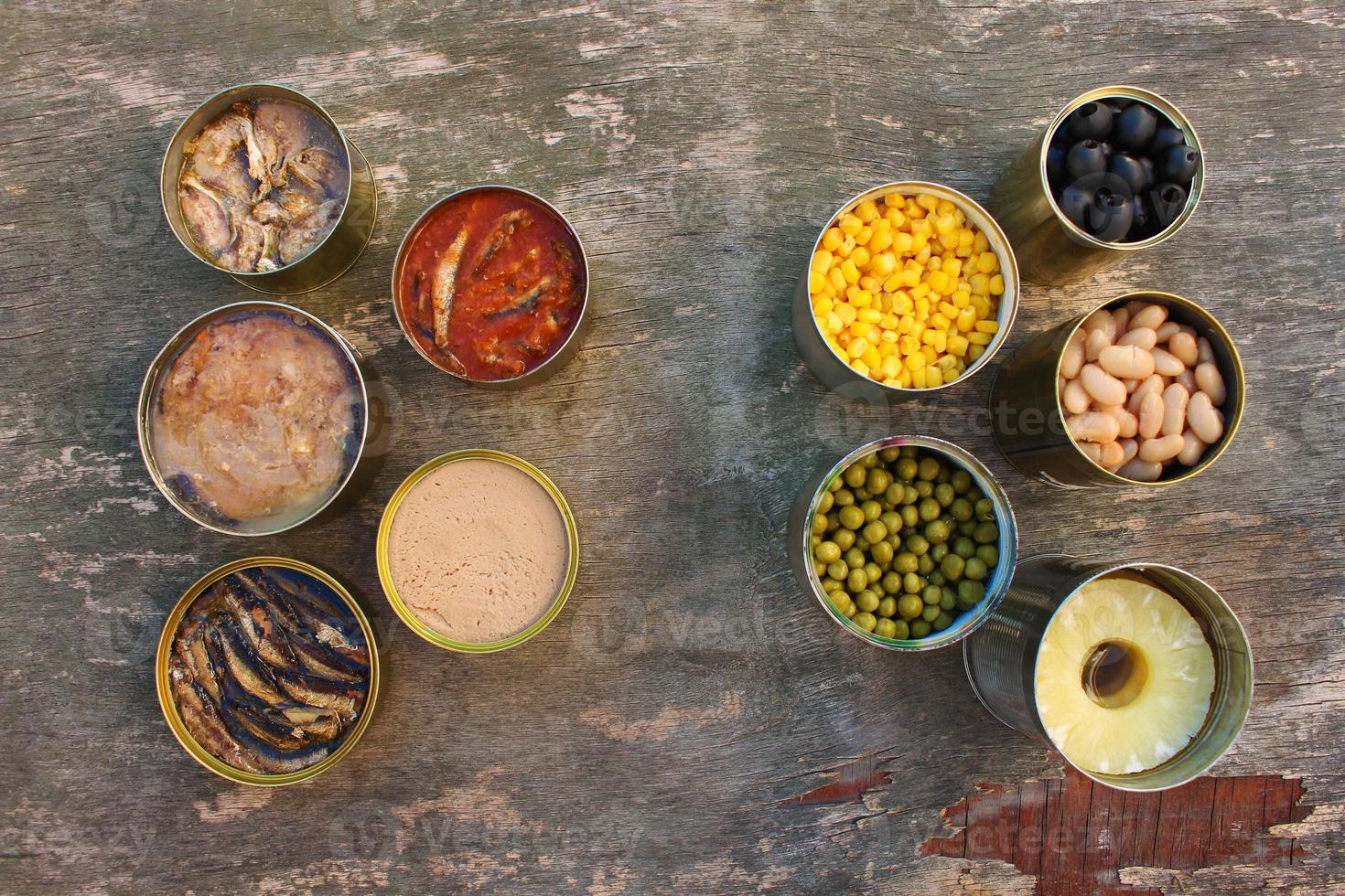 Different open canned food on old wooden background. Top view. Flat lay. photo