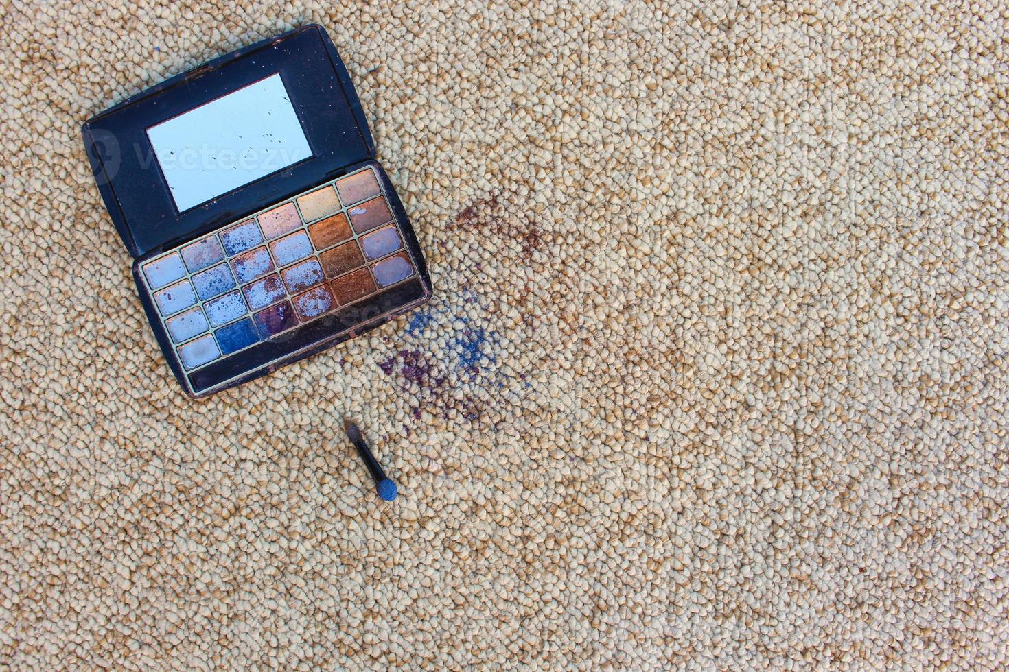 Eye shadow fell and scattered on carpet. Top view. photo