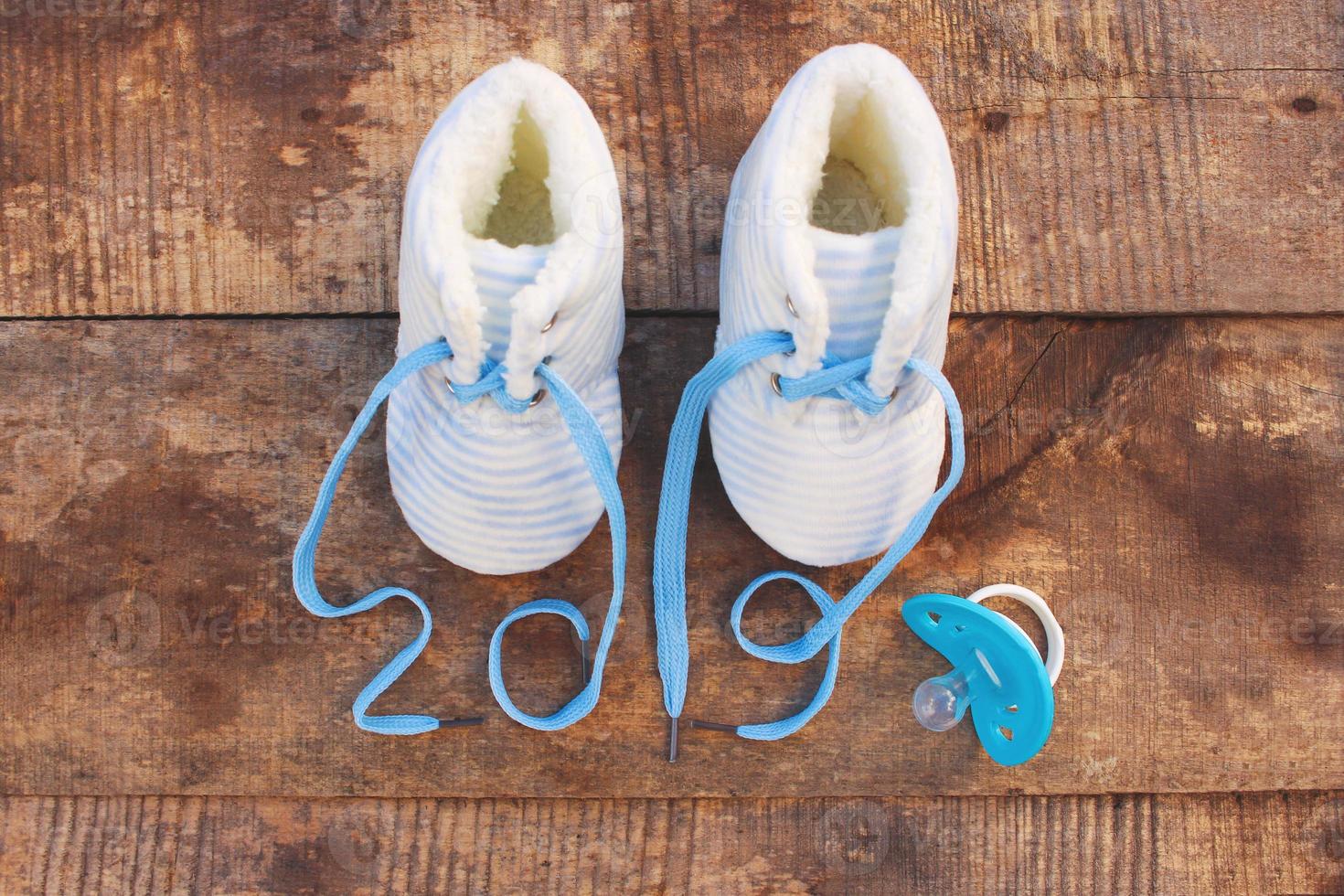 2019 new year written laces of children's shoes and pacifier on old wooden background. Top view. Flat lay. Toned image. photo