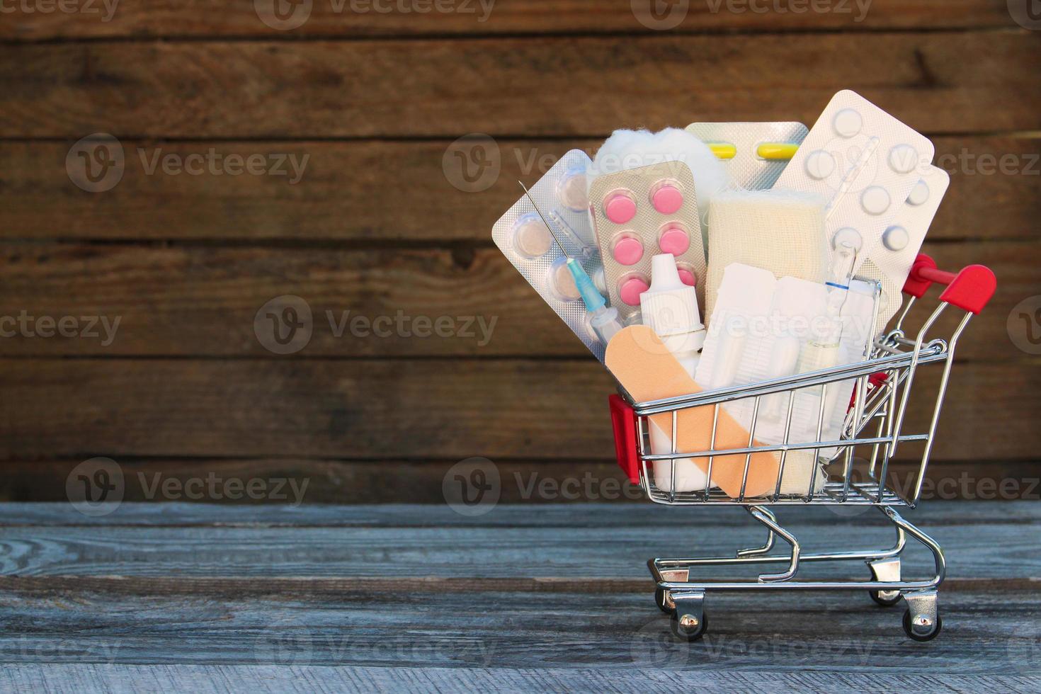 Shopping cart with medication on old wooden background. photo