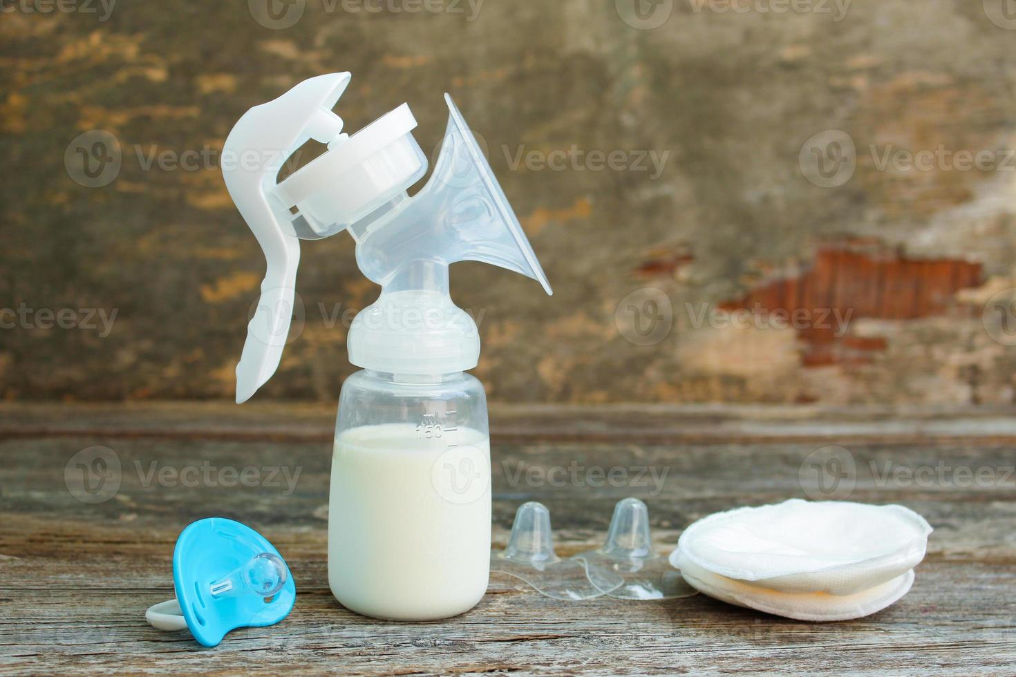 Breast pump of milk, pacifier and silicone breast pads for feeding on old wooden background. photo