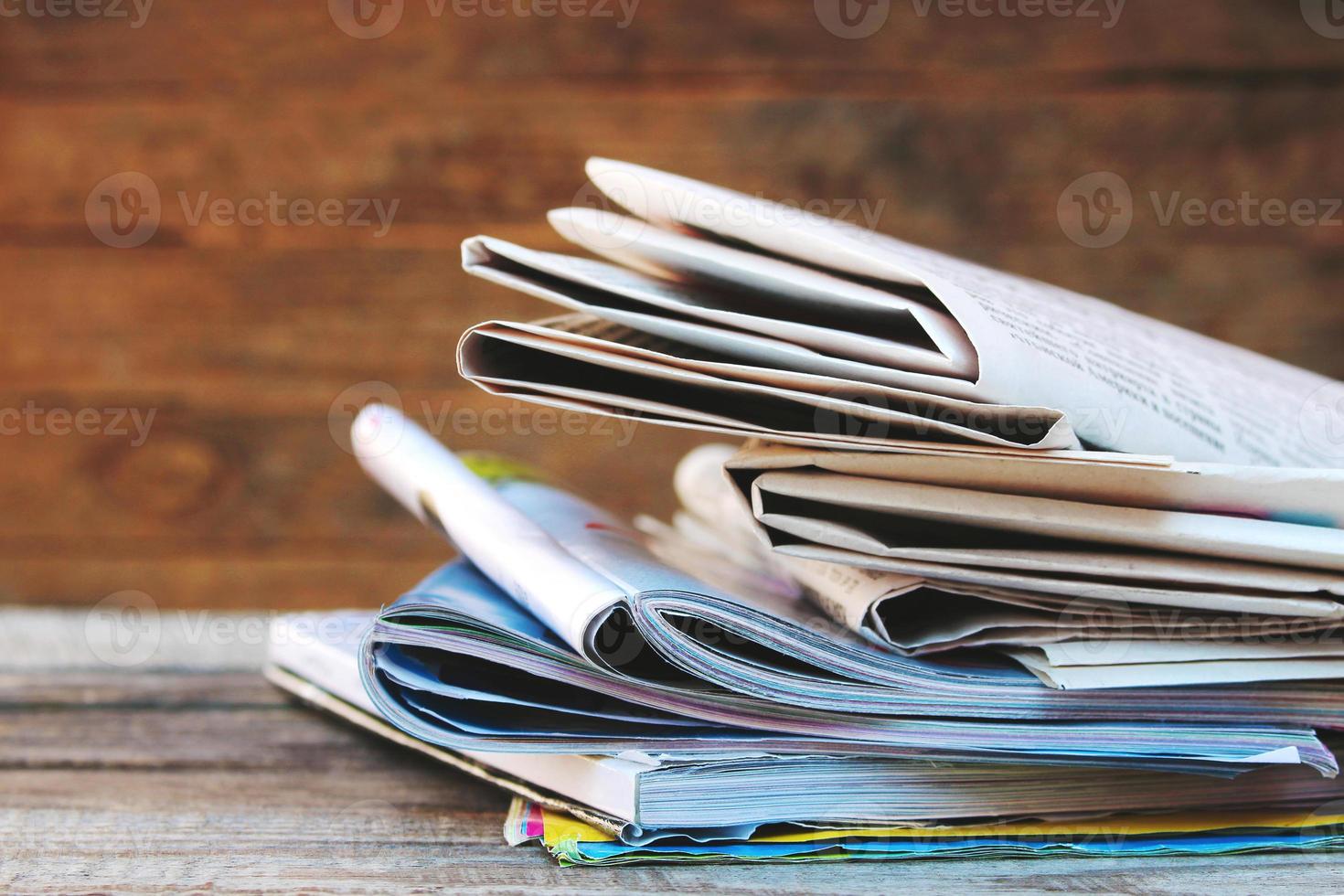 Newspapers and magazines on old wood background. Toned image. photo