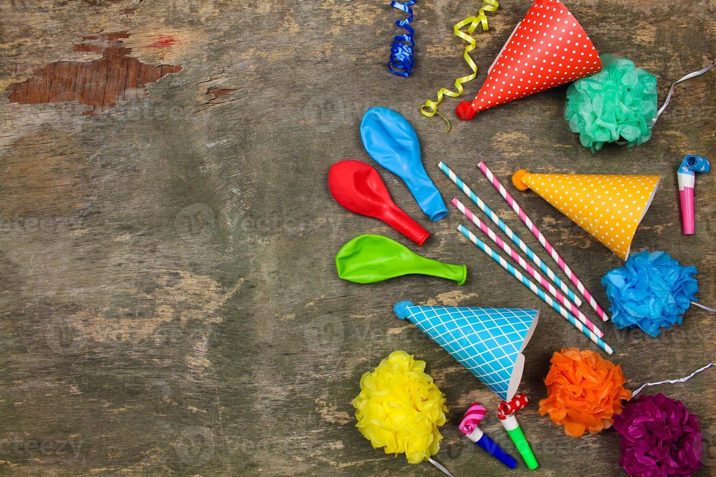 Holiday hats, whistles, balloons on old wooden background. Concept of children's birthday party. Top view. photo