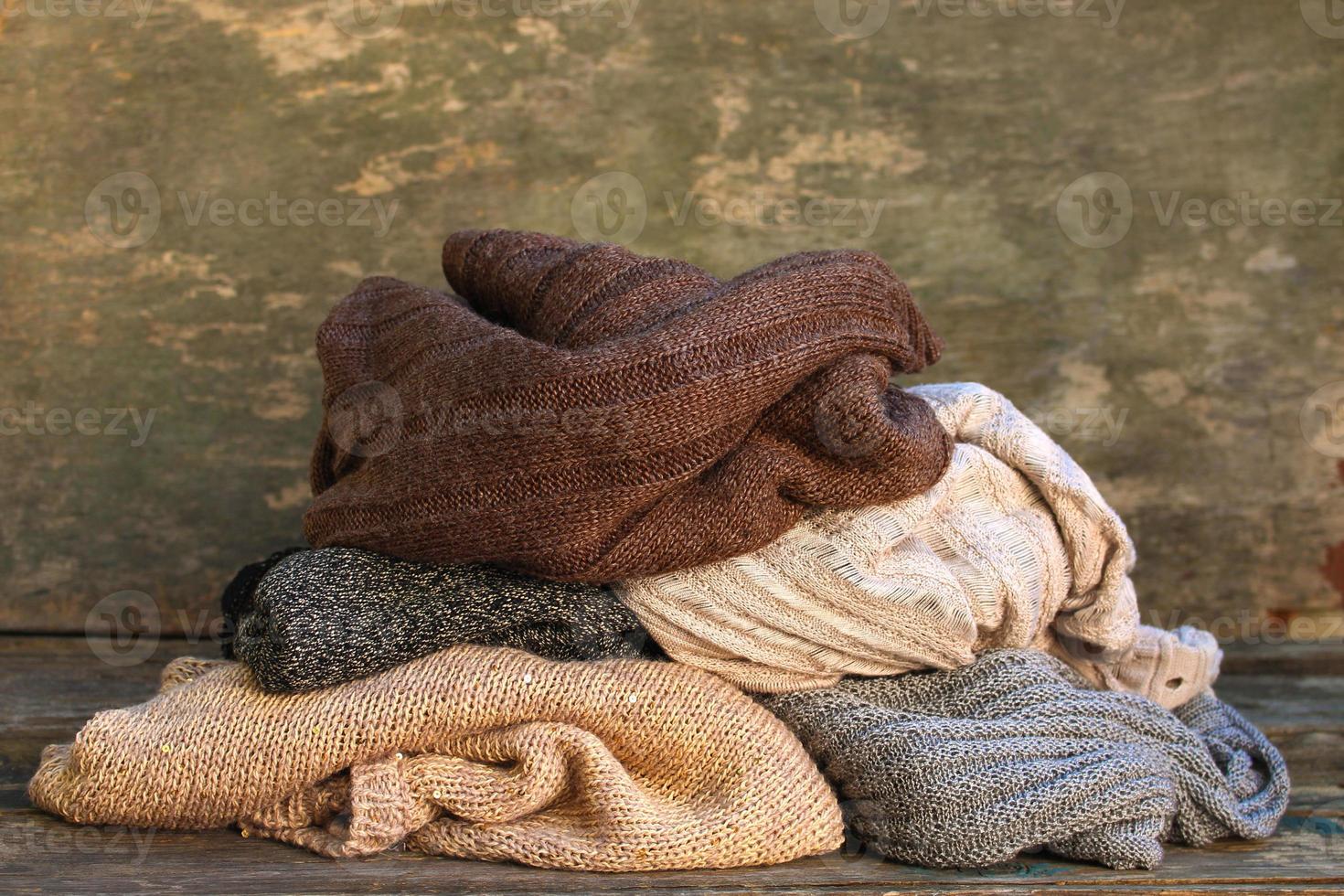 Pile of colorful warm clothes on wooden background. photo