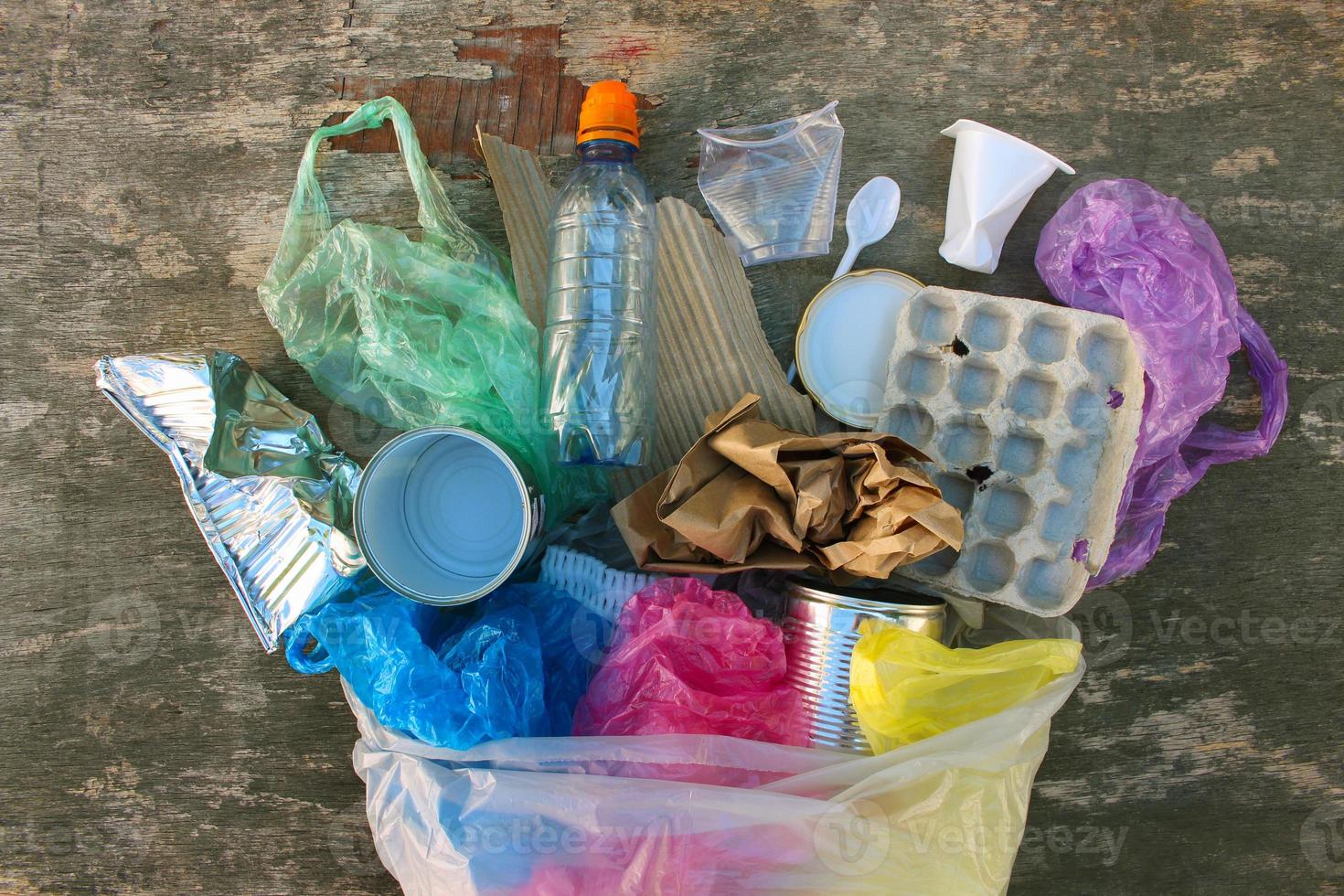 Garbage bag with different trash on wooden background. Top view. Flat lay. photo