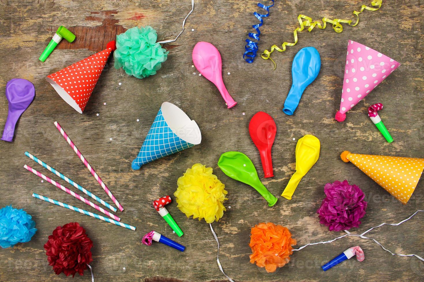 Holiday hats, whistles, balloons on old wooden background. Concept of children's birthday party. Top view. photo