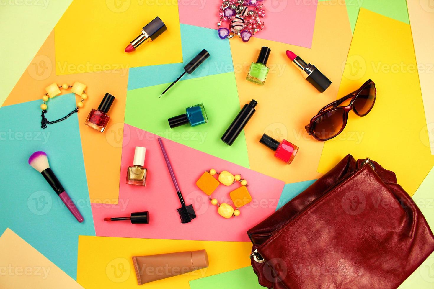 Things from open lady purse. Cosmetics and women's accessories fell out of red handbag on colourful background. Top view. Flat lay. photo