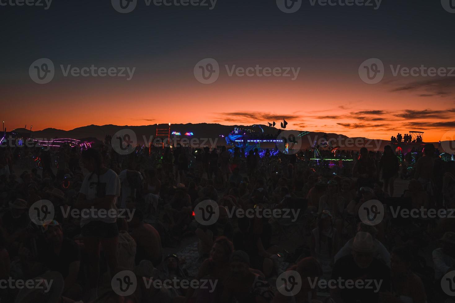 personas caminando hacia puesta de sol a un festival en el Desierto a el ardiente hombre festival. foto