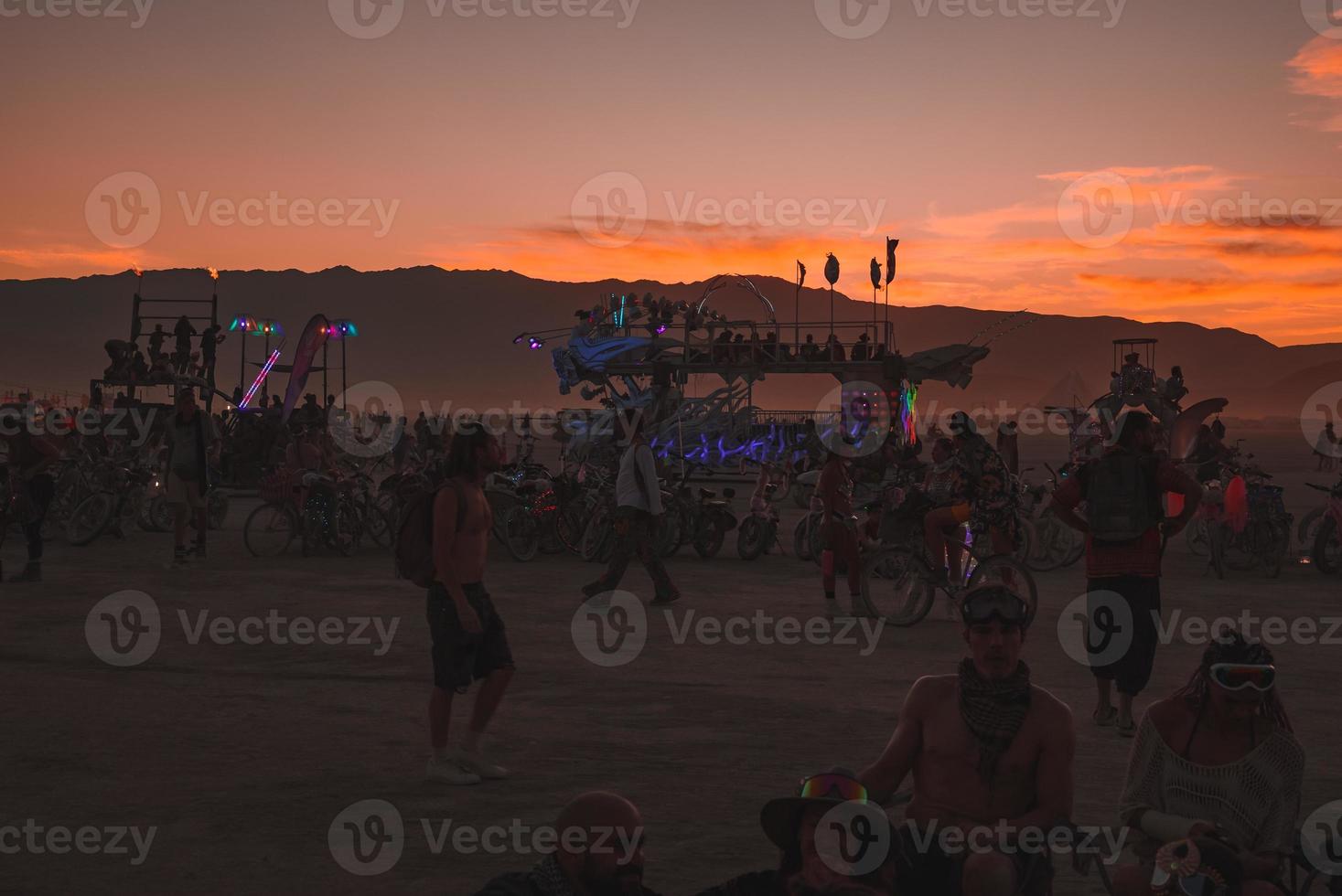 personas caminando hacia puesta de sol a un festival en el Desierto a el ardiente hombre festival. foto