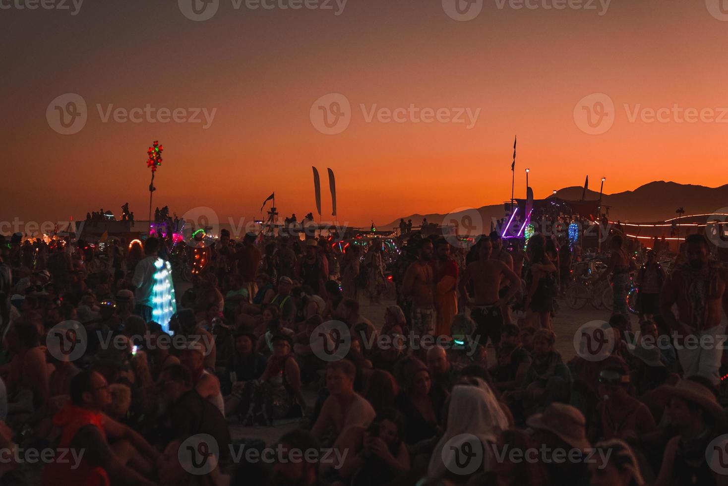 personas caminando hacia puesta de sol a un festival en el Desierto a el ardiente hombre festival. foto