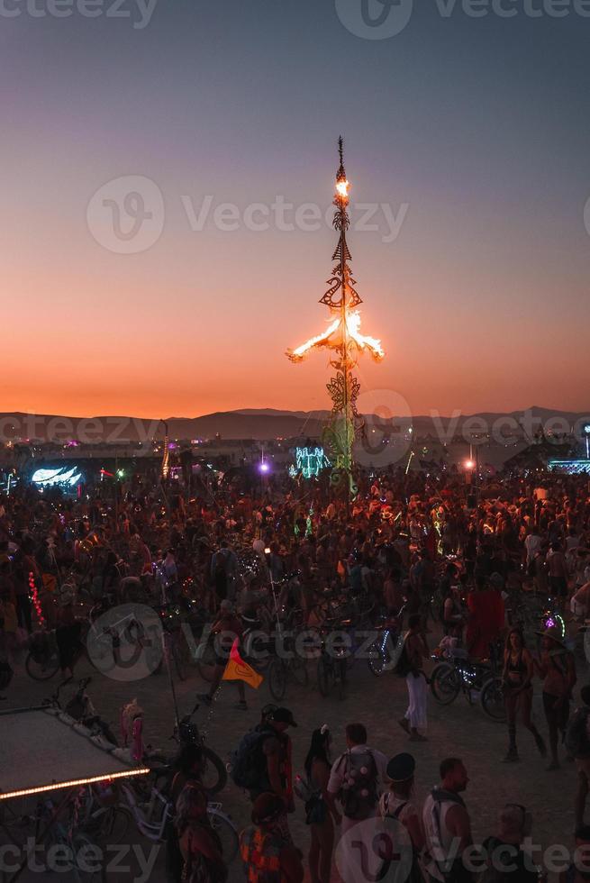 personas caminando hacia puesta de sol a un festival en el Desierto a el ardiente hombre festival. foto