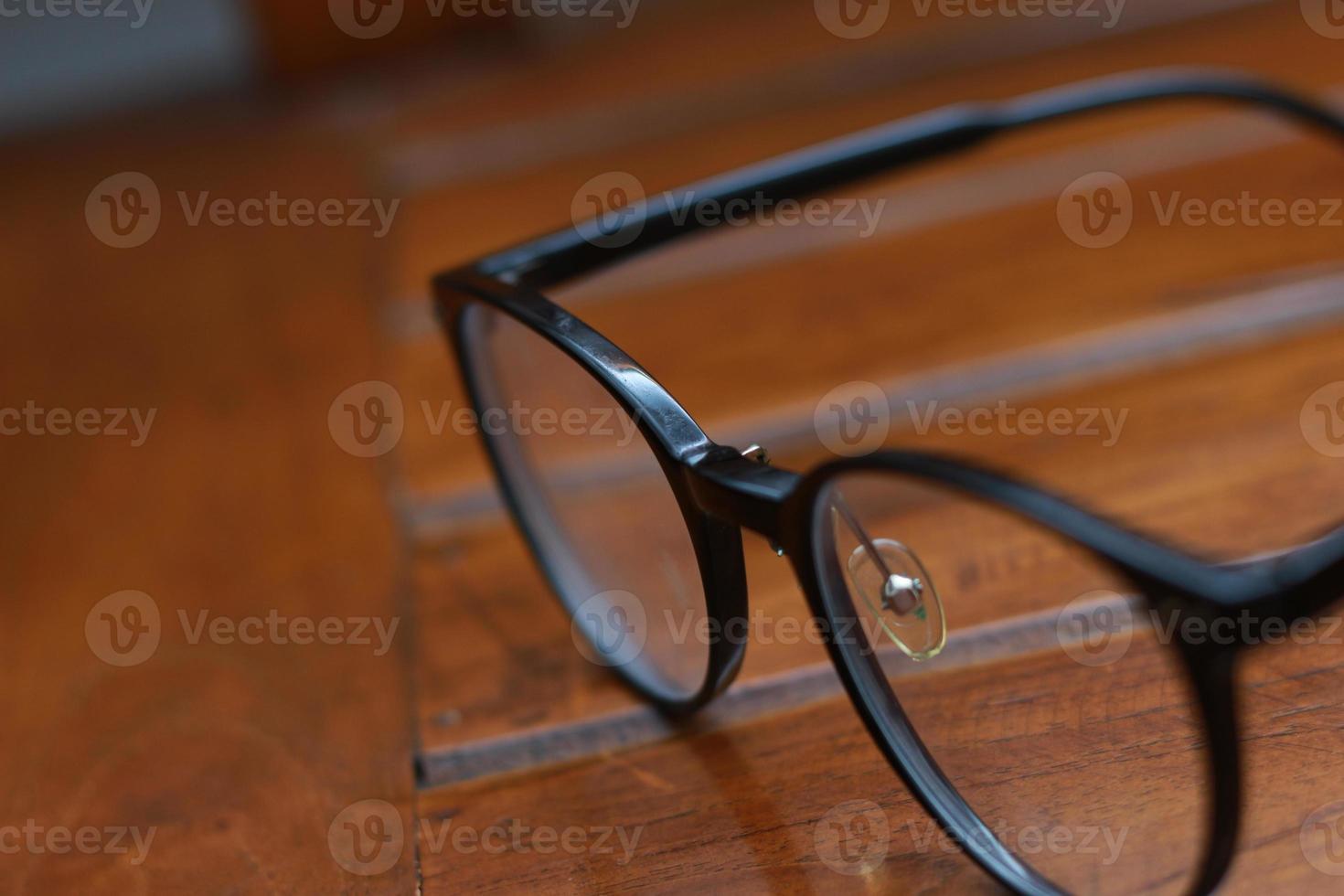 a close up of eyeglasses with black frames isolated natural patterned wooden background. photo