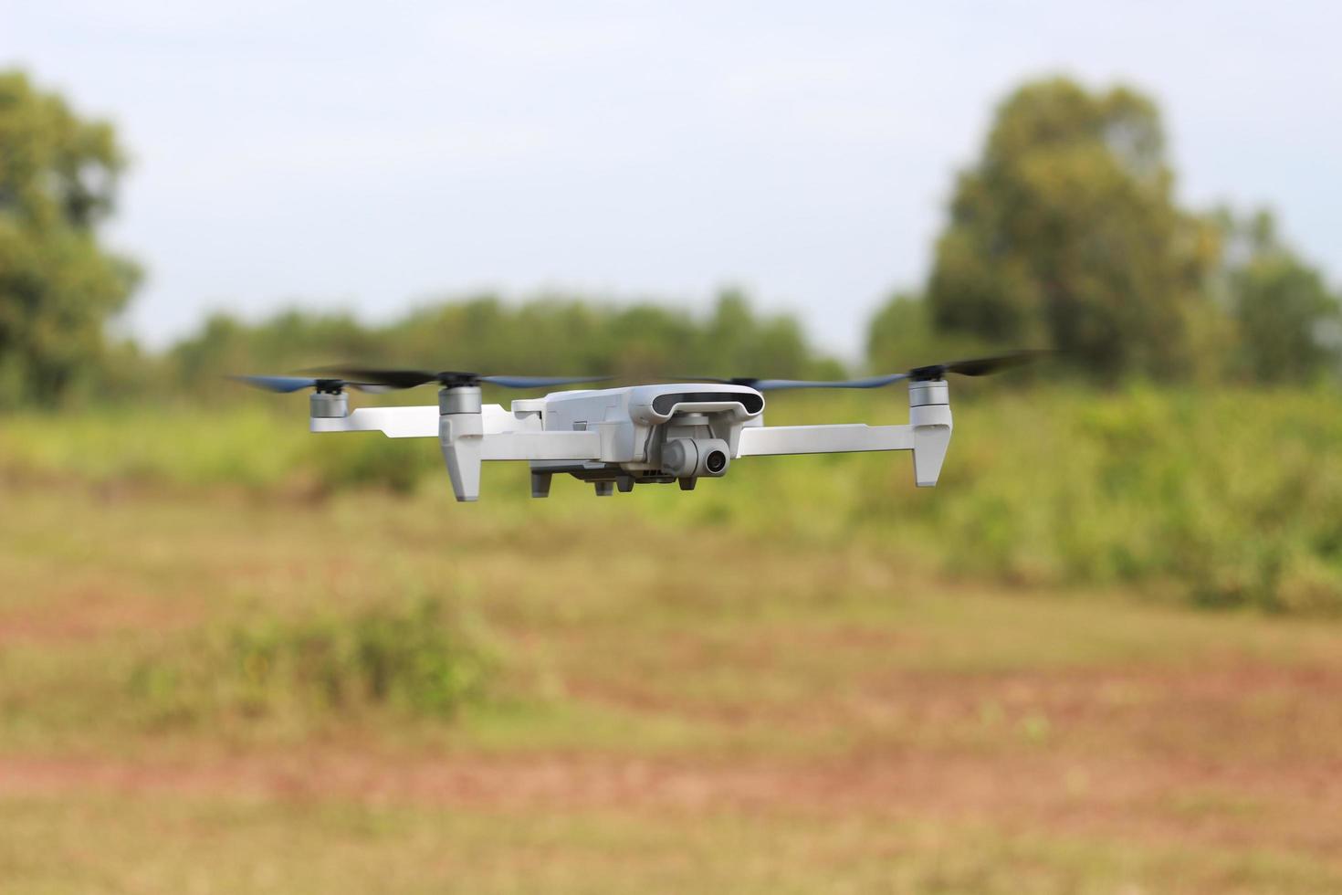 a photo of a drone flying with a blurry propeller against a green open space background. technology photo concept.