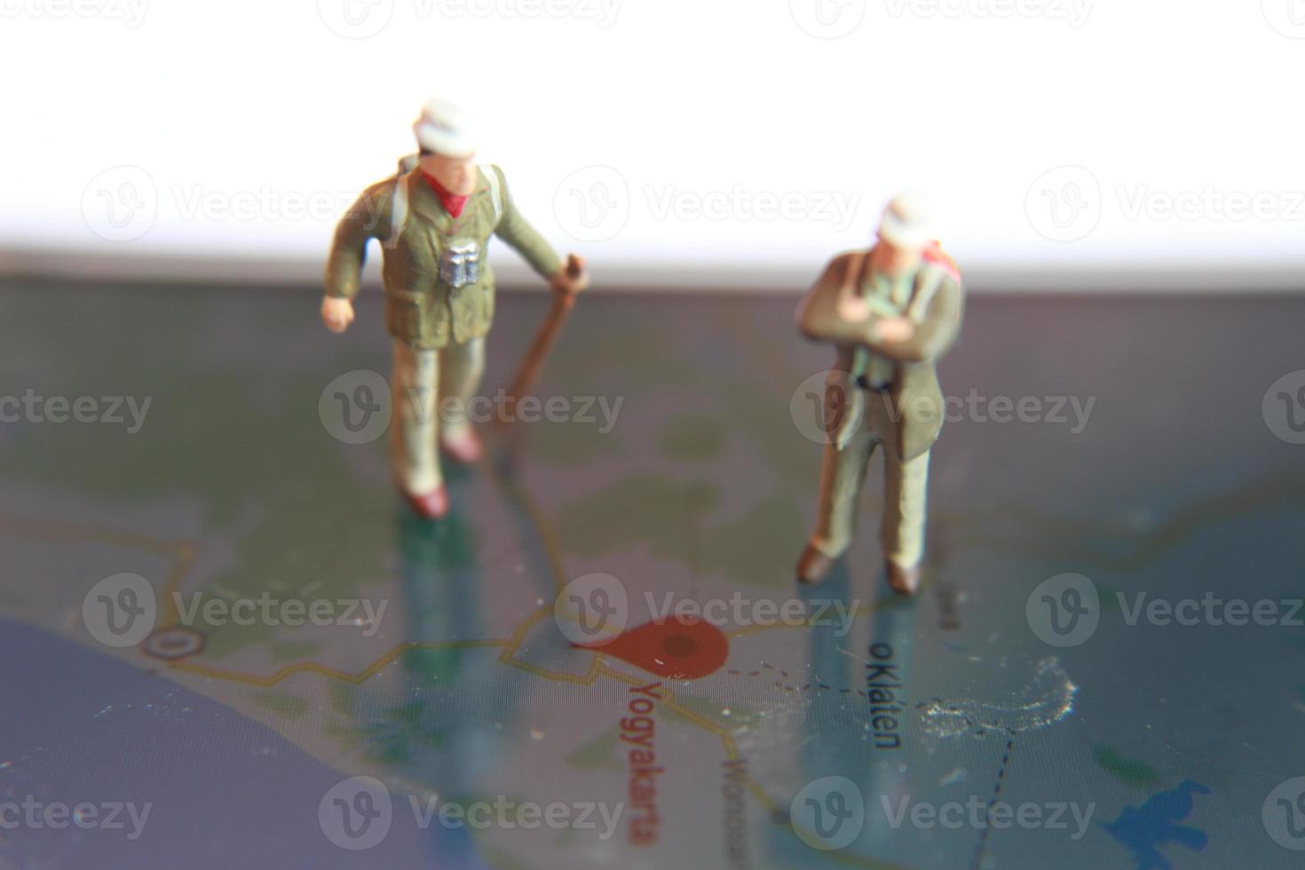 miniatura figura de un explorador posando en un digital mapa vía un móvil teléfono foto