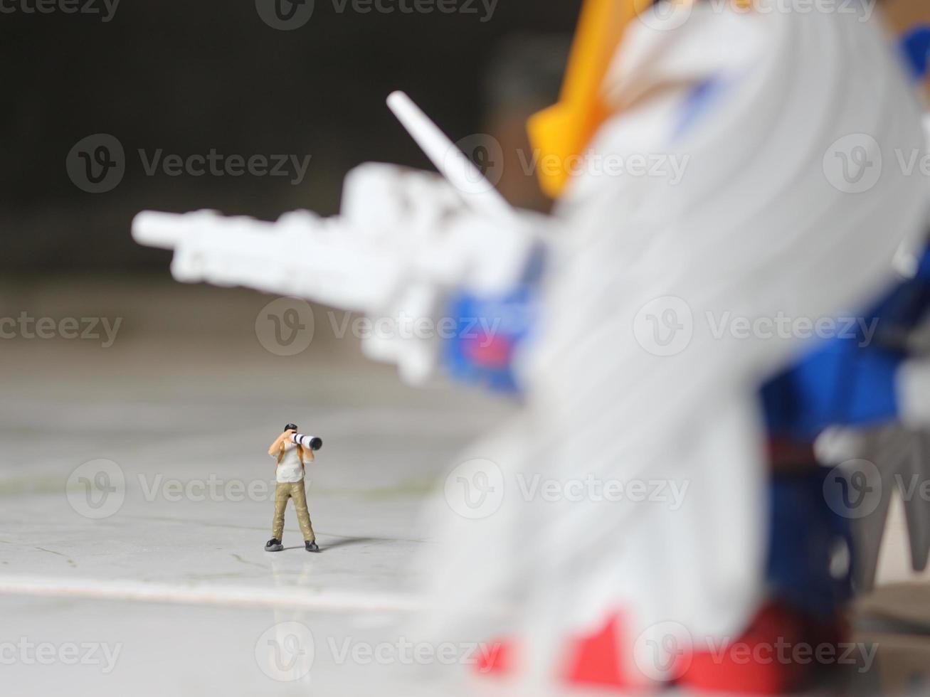 miniature figure of a photographer taking a photo of a robot.