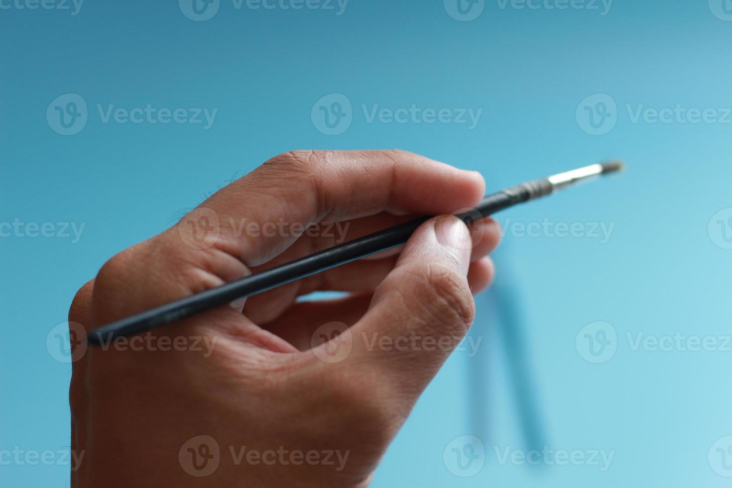 a close up of a hand holding a painting brush photo