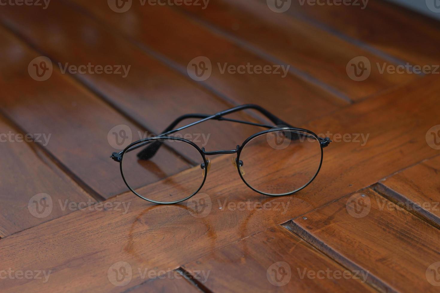 a close up of eyeglasses with black frames isolated natural patterned wooden background. photo