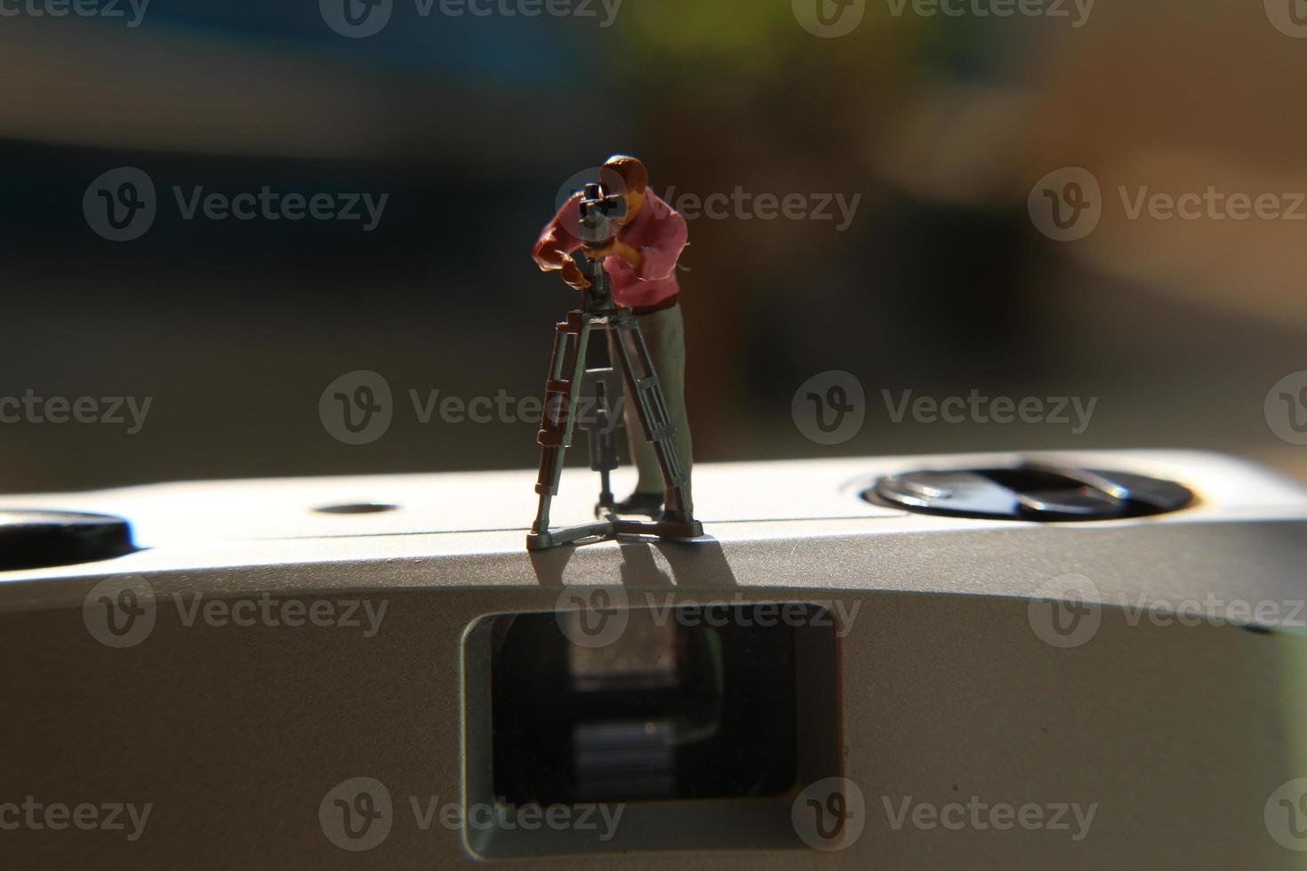 miniature figure of a videographer recording on an analog camera. photo