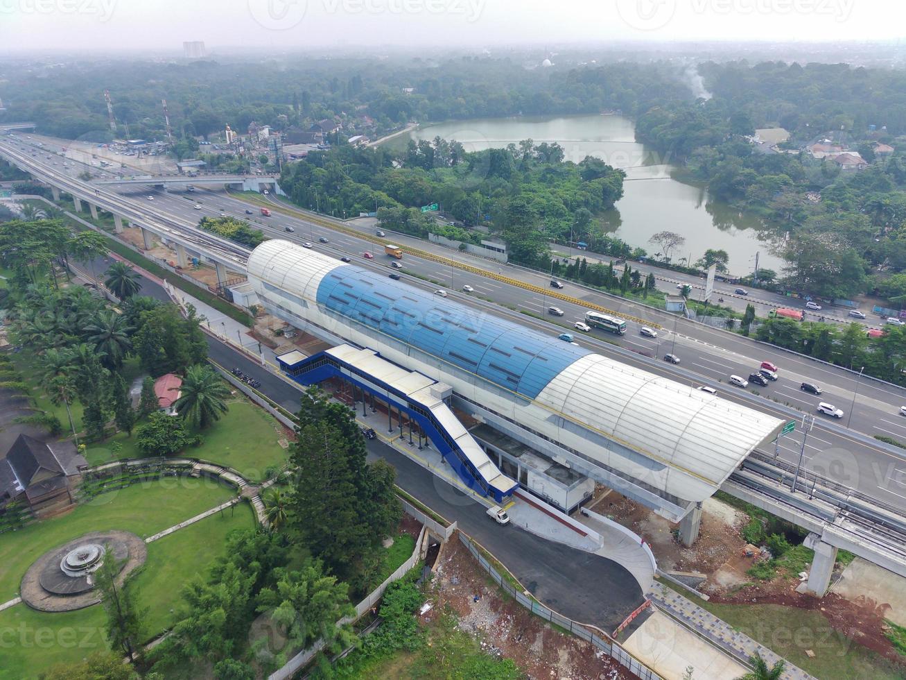 aerial view of an LRT station under construction, above the expressway and next to a park. photo