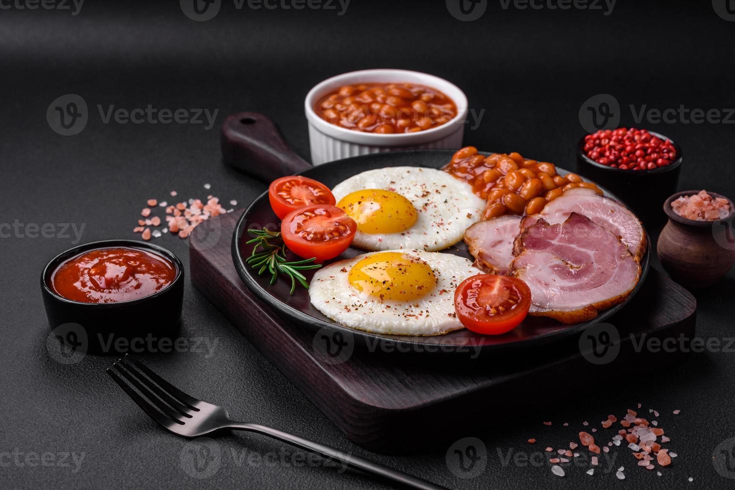 Delicious nutritious English breakfast with fried eggs and tomatoes photo