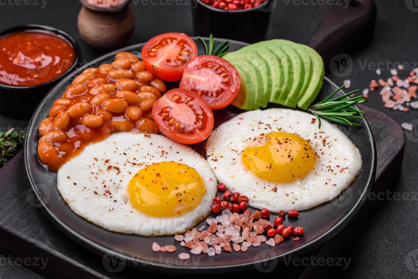 Delicious nutritious English breakfast with fried eggs, tomatoes and avocado photo