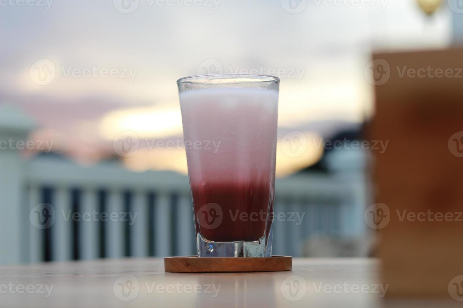 a glass of red velvet latte served cold on the table. photo